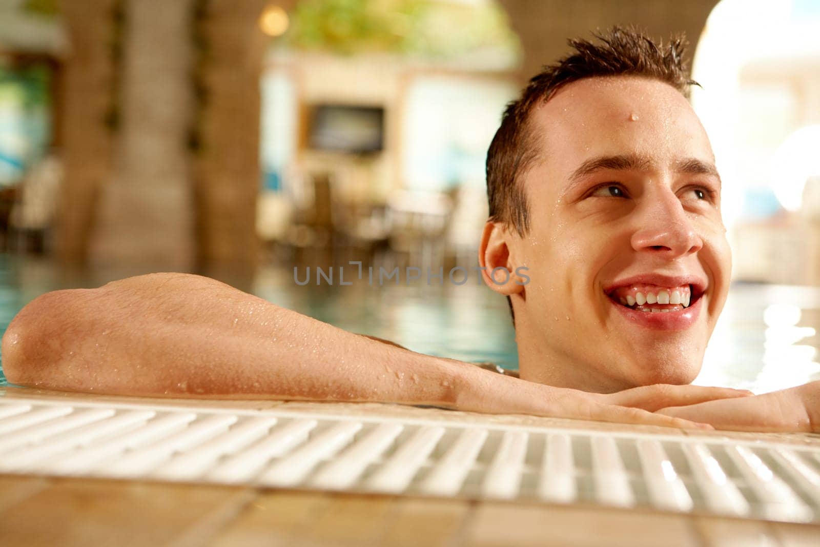 Portrait of happy guy laughing in swimming pool