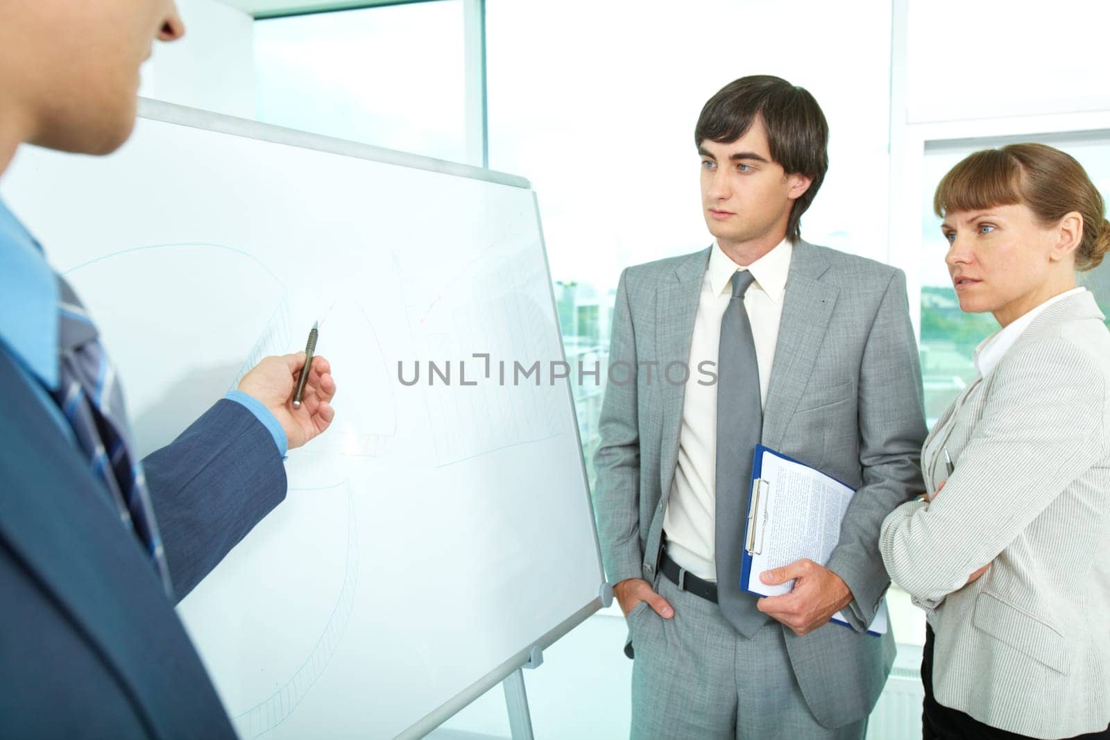 A group of colleagues looking at whiteboard while their employer explaining them something