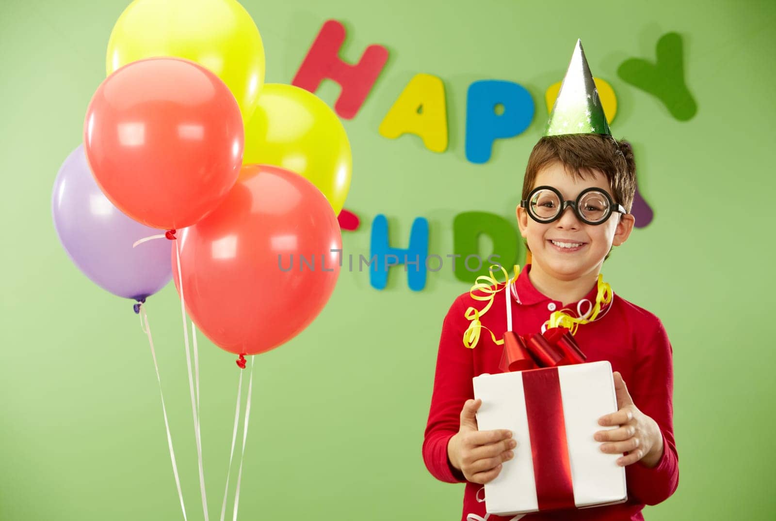 Portrait of happy lad in funny eyeglasses on birthday party with giftbox