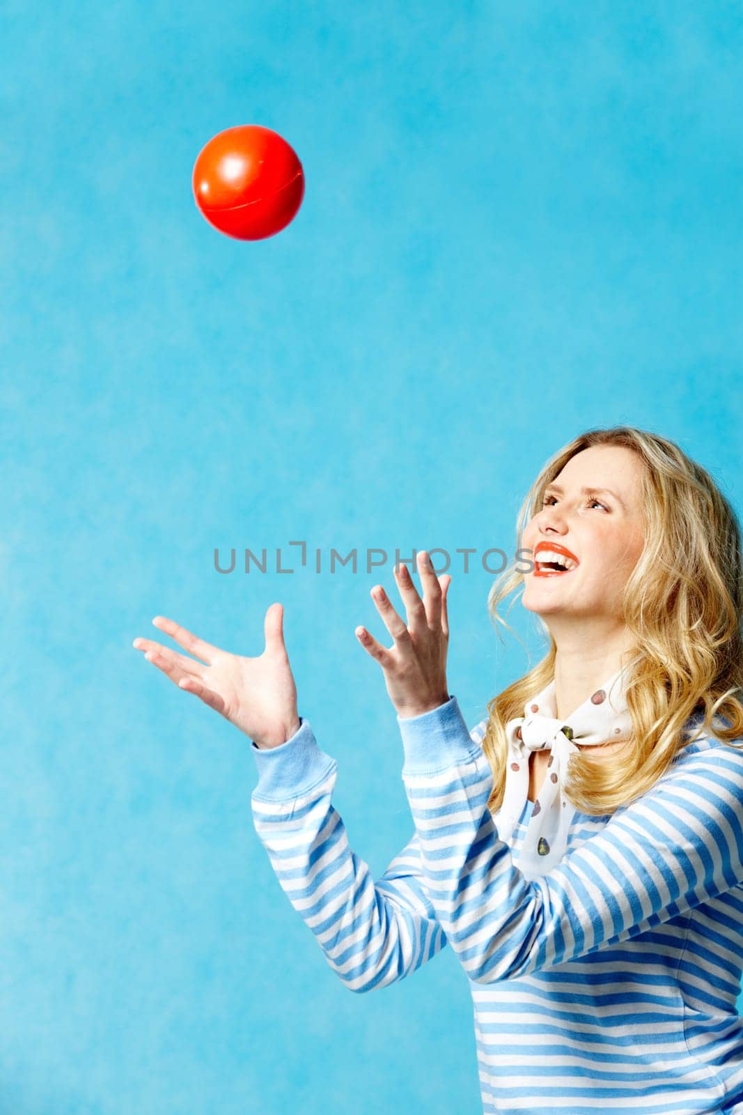 Portrait of young cheerful woman playing with a ball