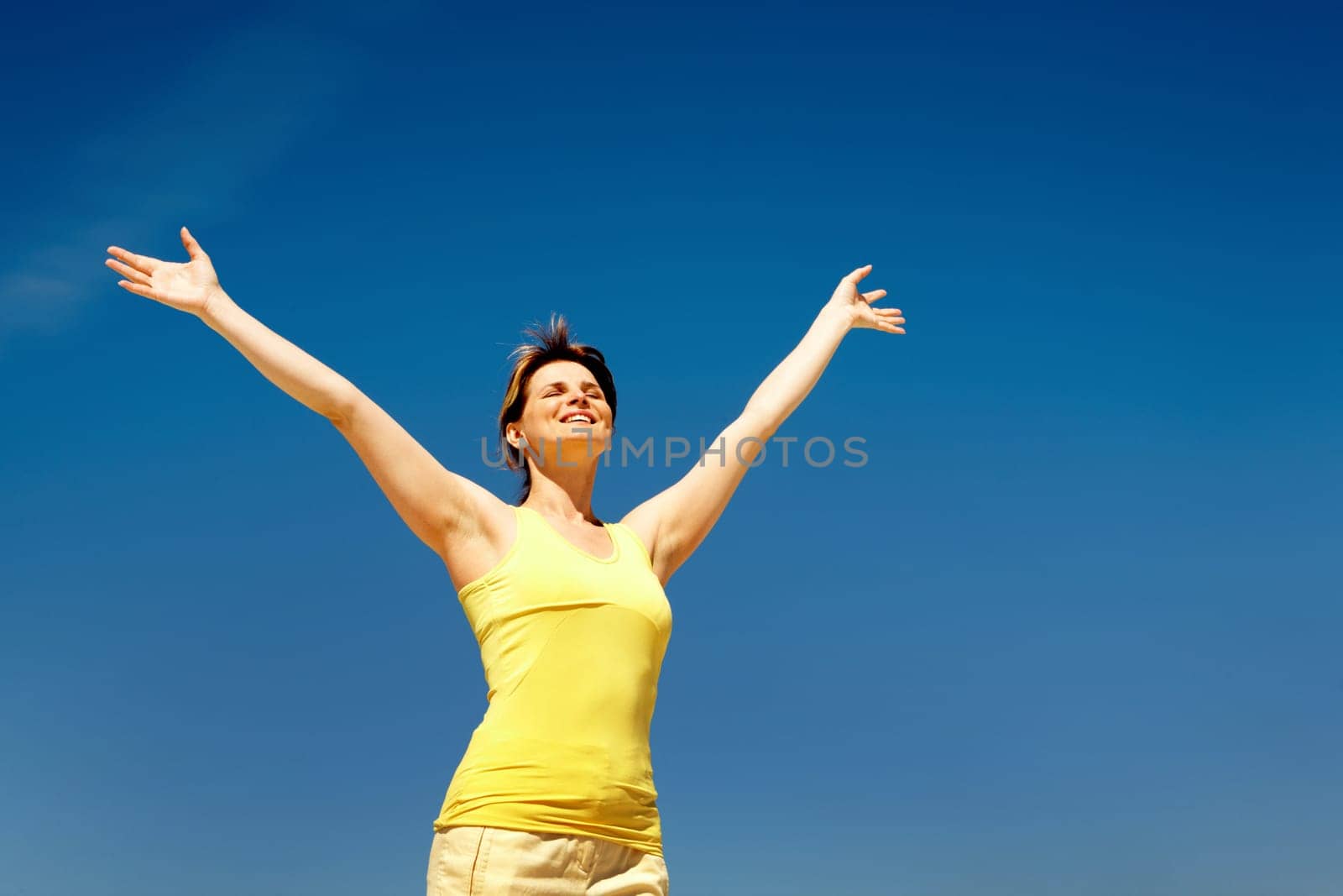 Image of joyful female in casual clothes enjoying herself against blue sky