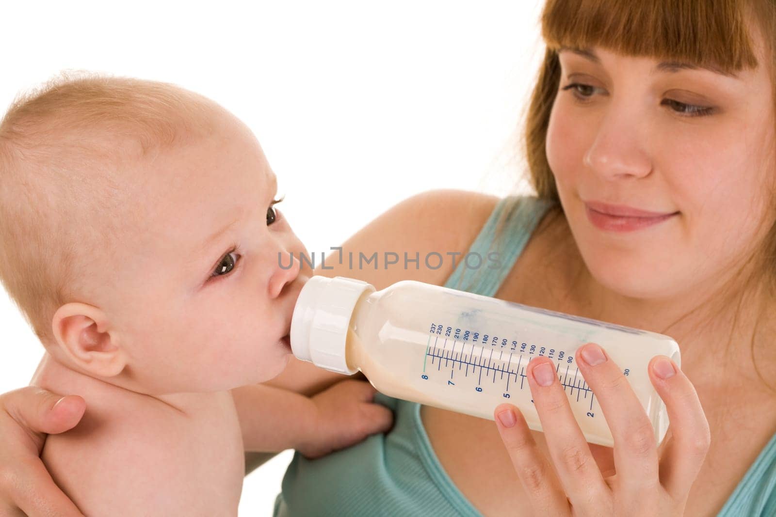 Careful mother holds bottle of milk while her adorable baby drinking it