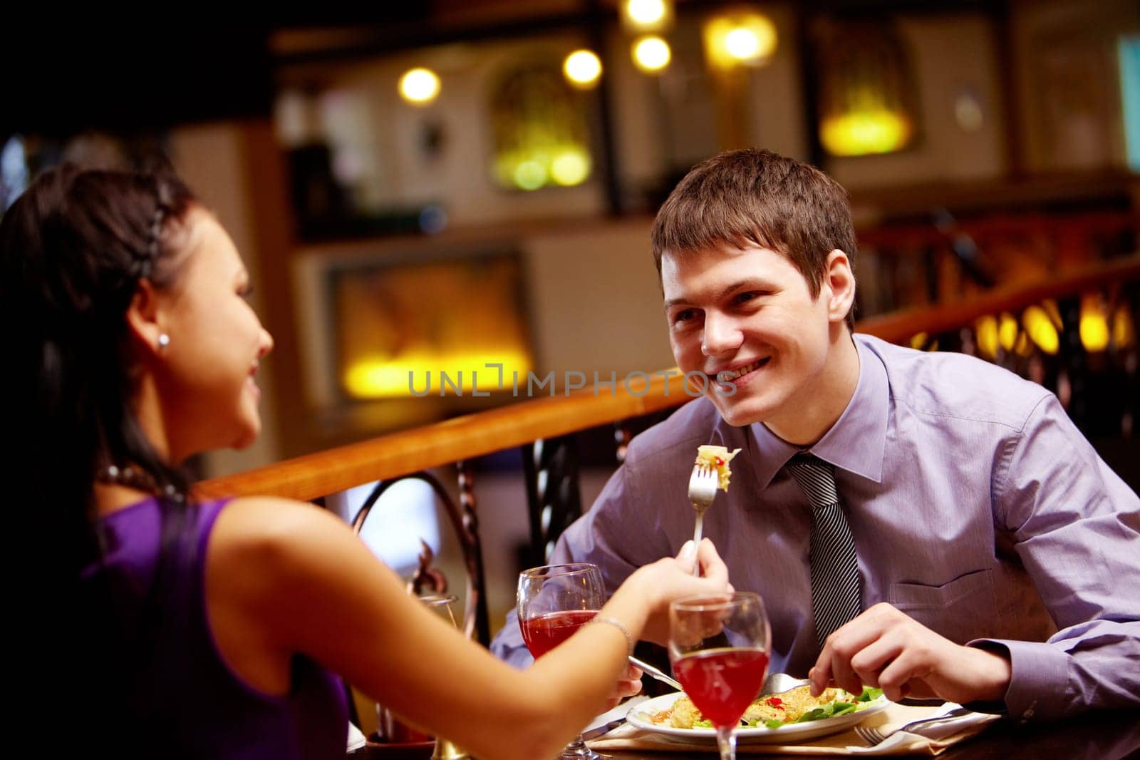 Woman spoon-feeds her boyfriend in the restaurant