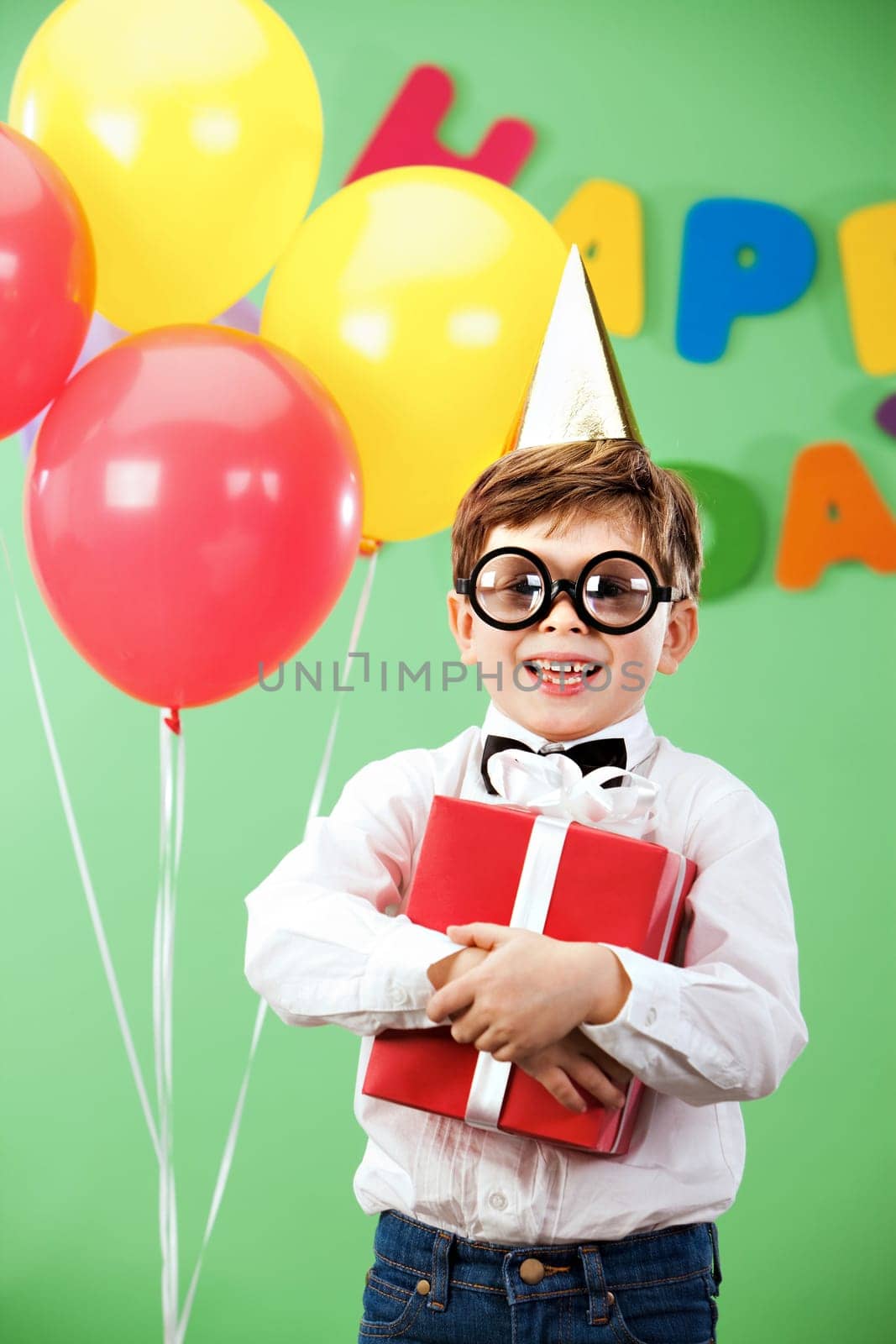 Portrait of happy lad in funny eyeglasses on birthday party with present