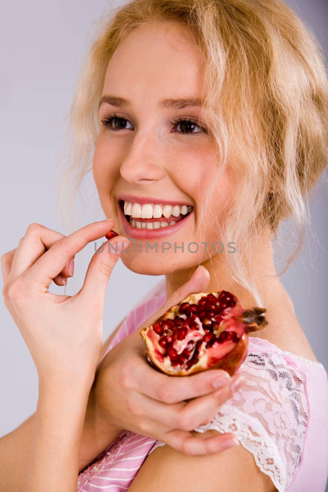 Portrait of a beautiful blonde woman with the pomegranate in her hand