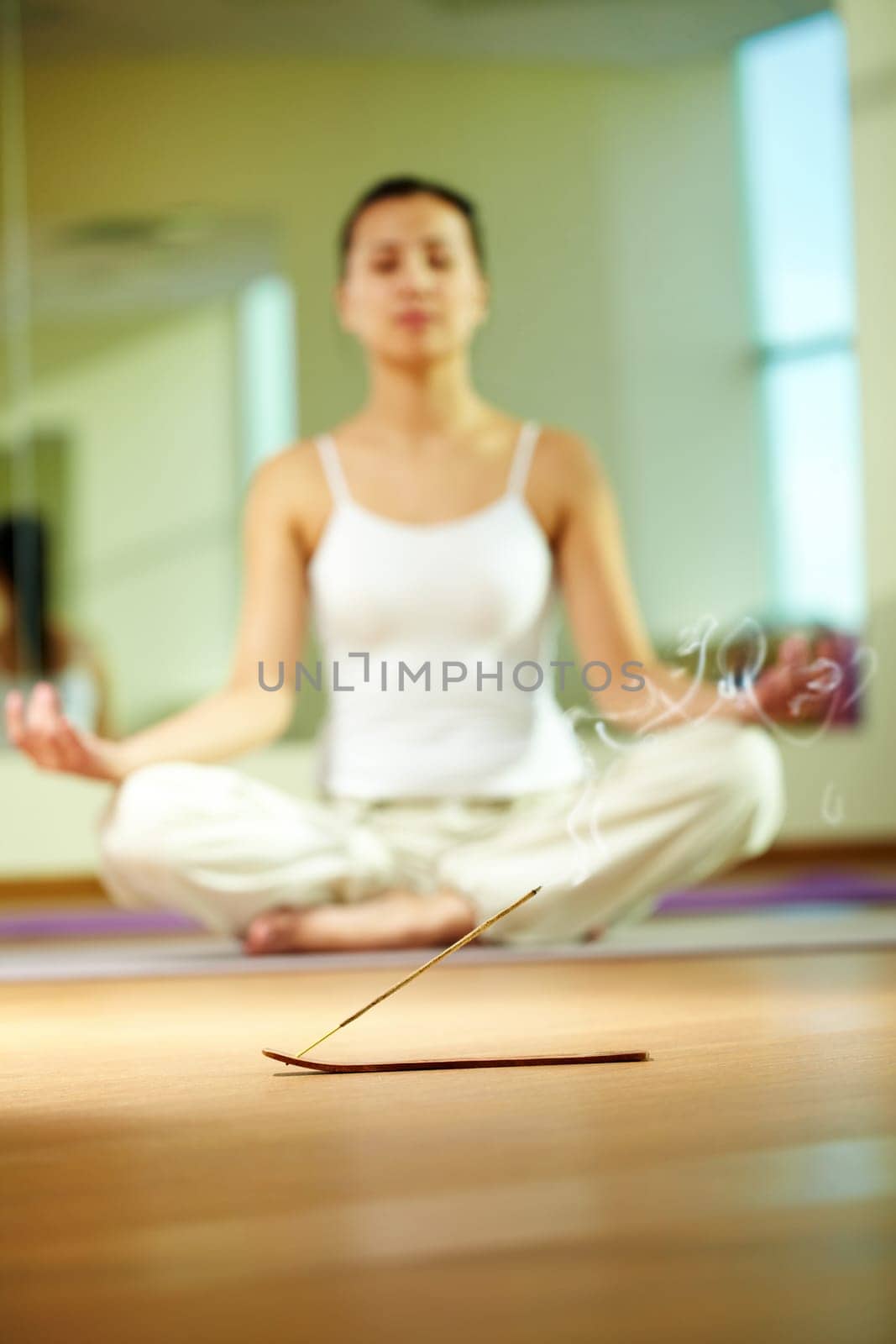 Close-up of smoking incense with serene girl doing yoga exercise on background