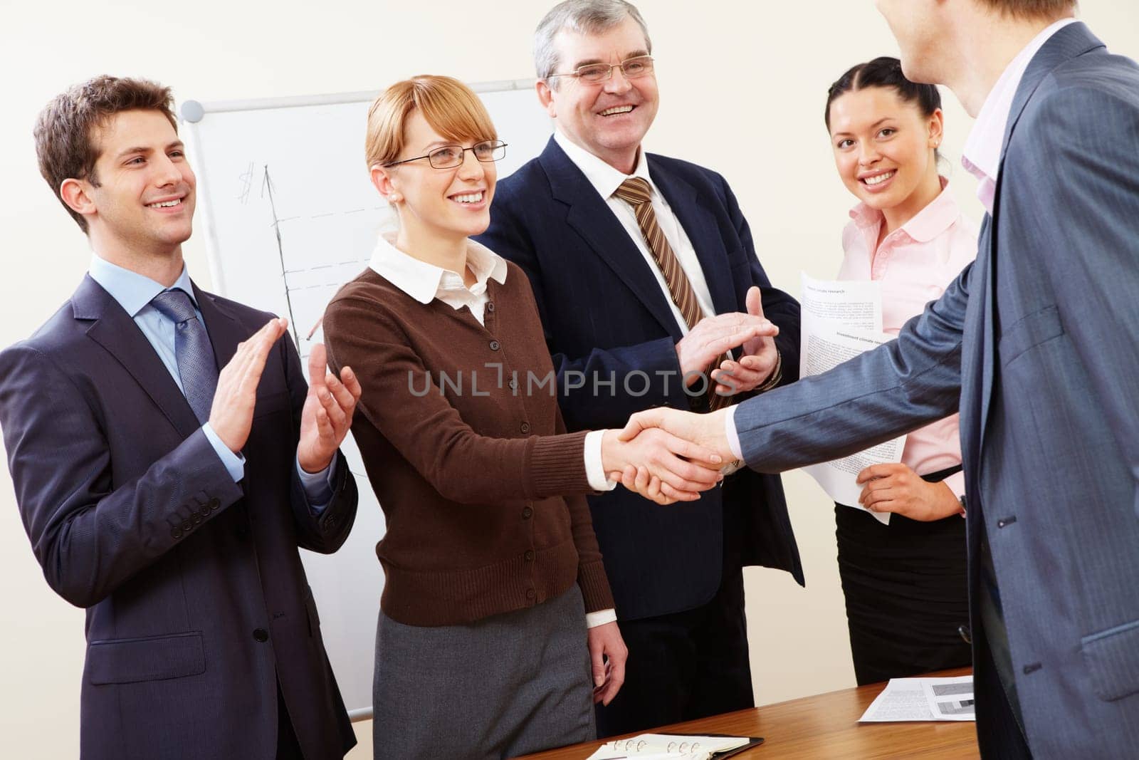 Photo of successful business partners handshaking after striking great deal with applauding people near by