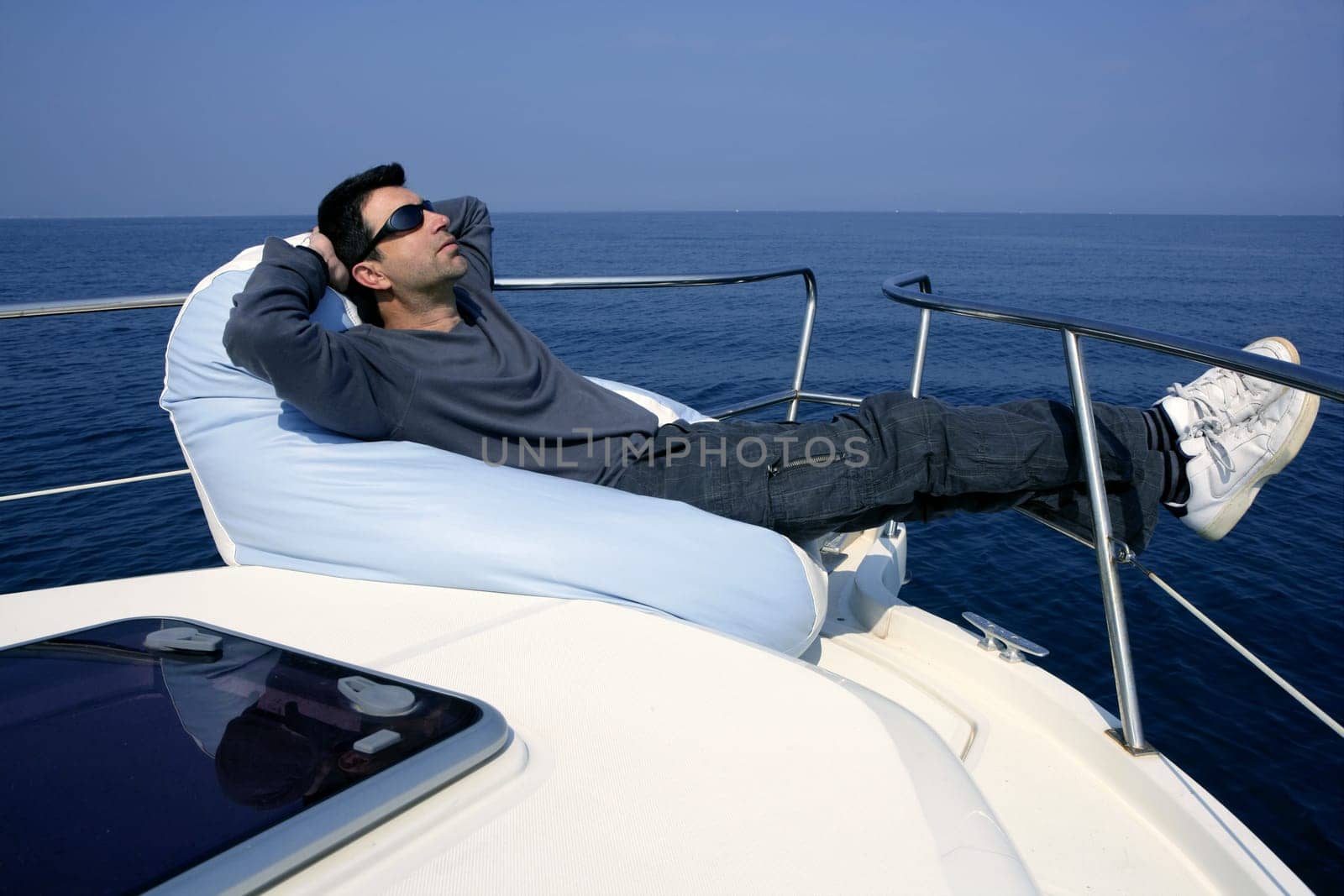 Man on bow boat relaxed on bean bag over blue sea