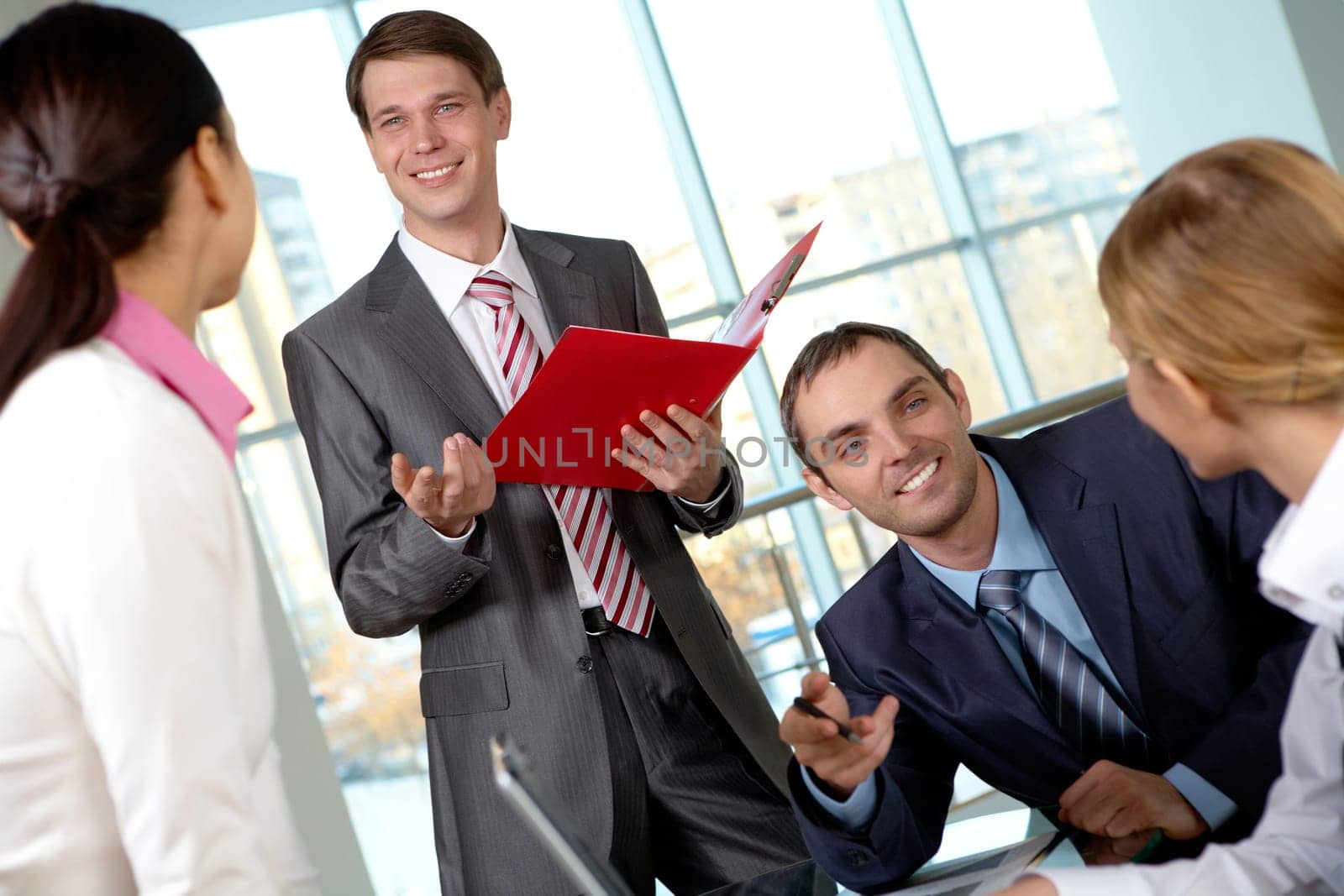 Image of several colleagues interacting at meeting in office