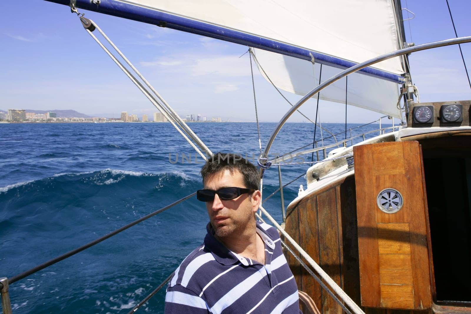 Sailor sailing blue tropical sea on sailboat in summer vacation