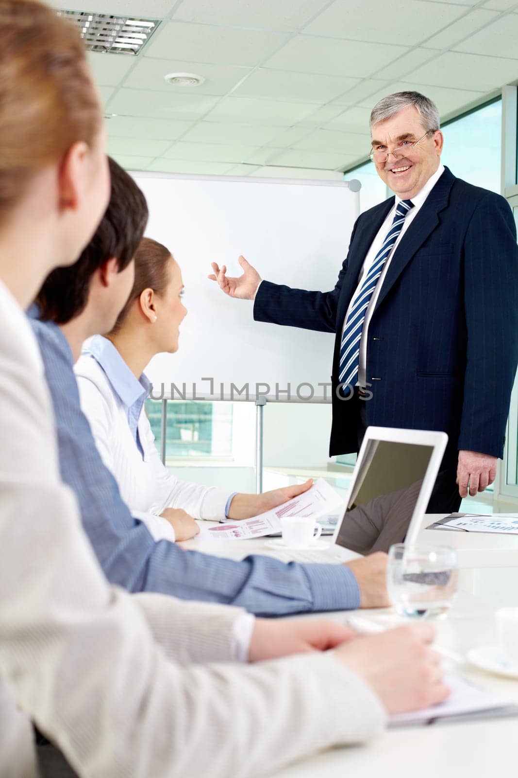 Senior business man showing something on a whiteboard to his colleagues