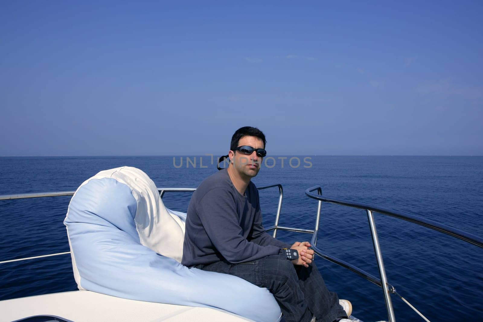 Man on bow boat relaxed on bean bag over blue sea