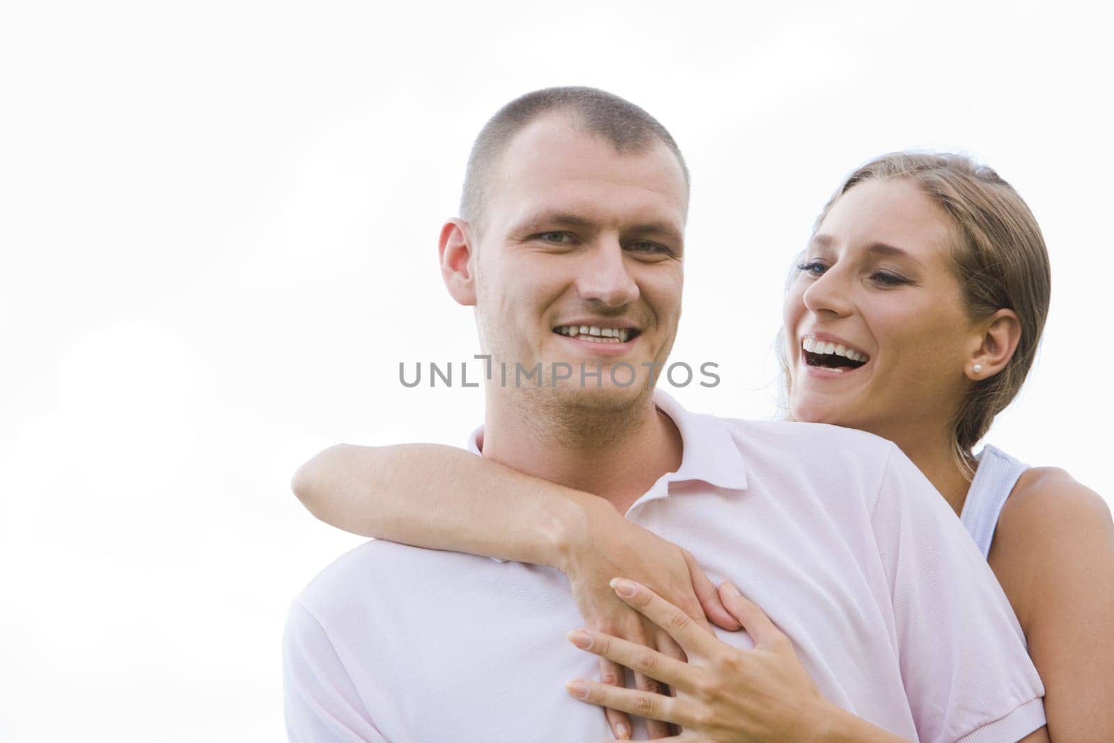 Laughing female embracing her husband on background of blue sky