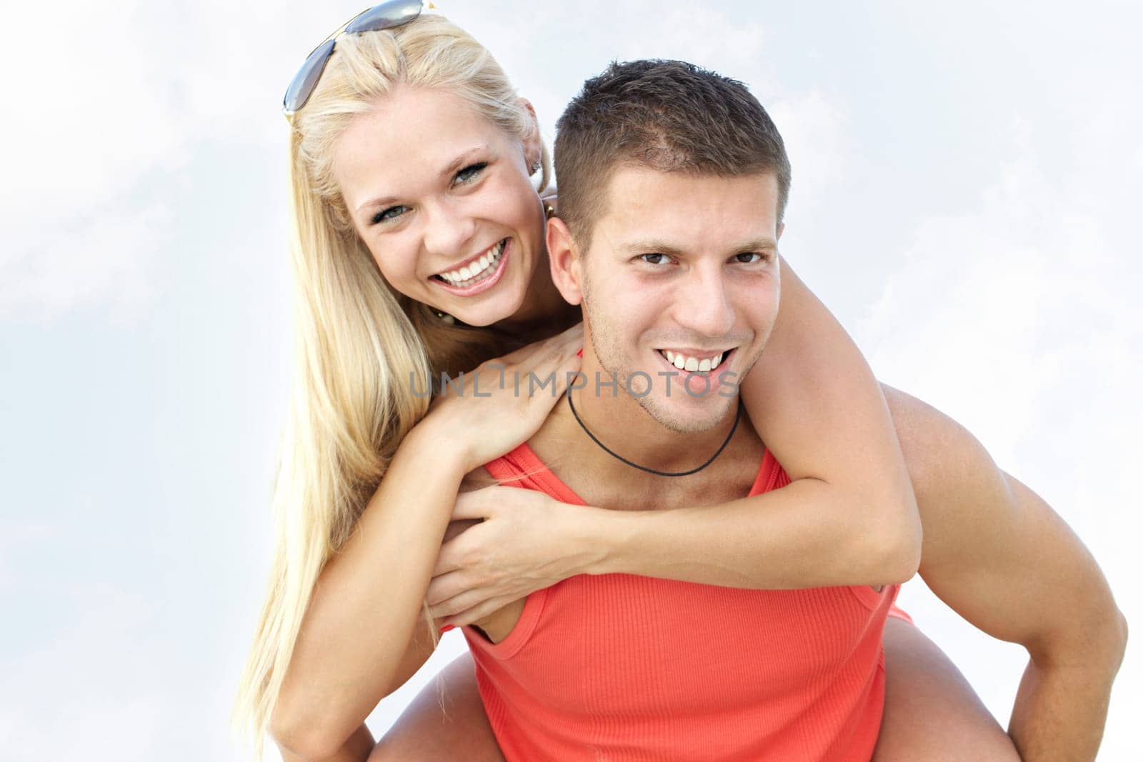 Portrait of a smiling man carrying his girlfriend piggyback
