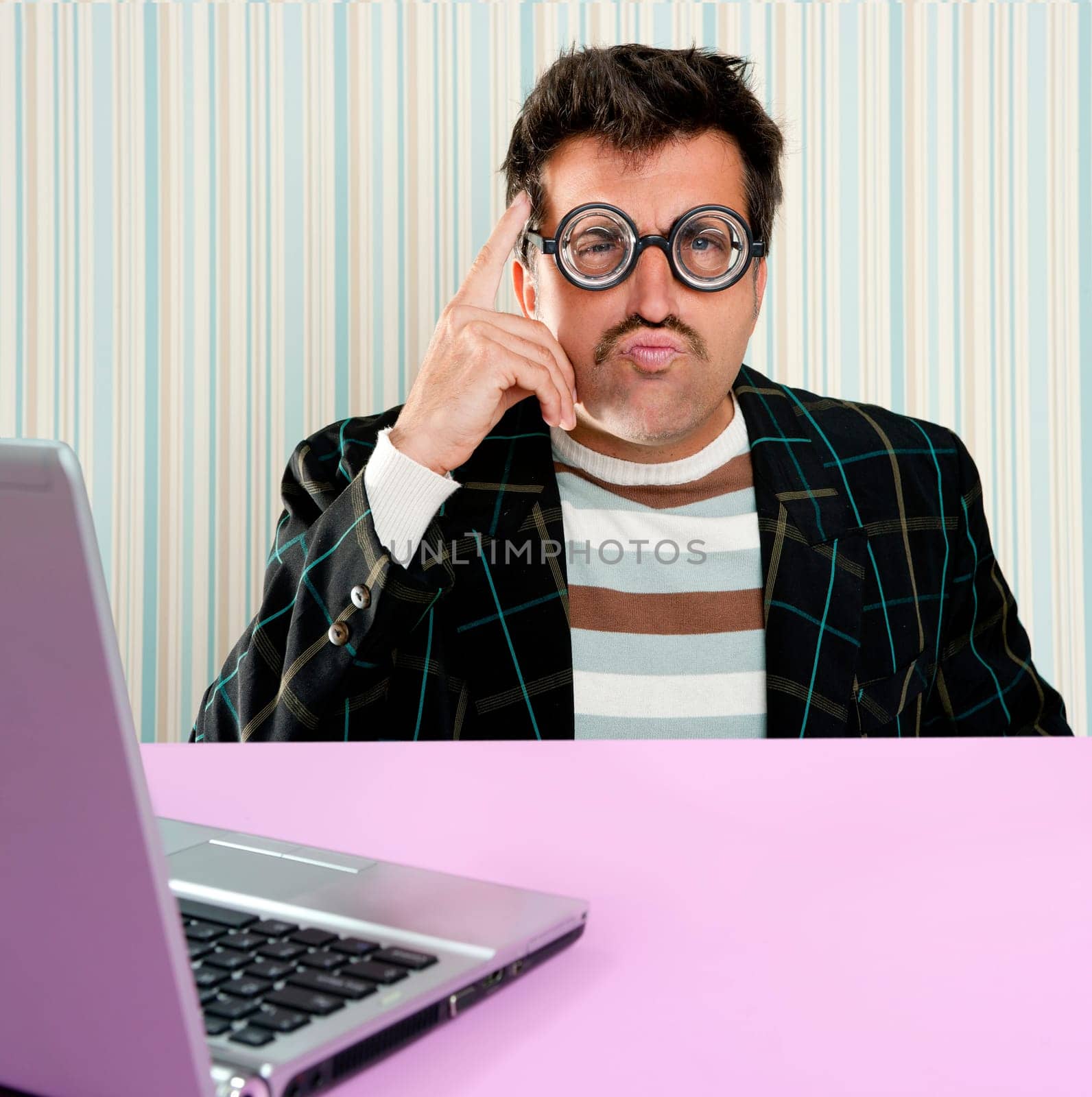 Nerd pensive man with myopic glasses and silly expression searching a solution in laptop computer