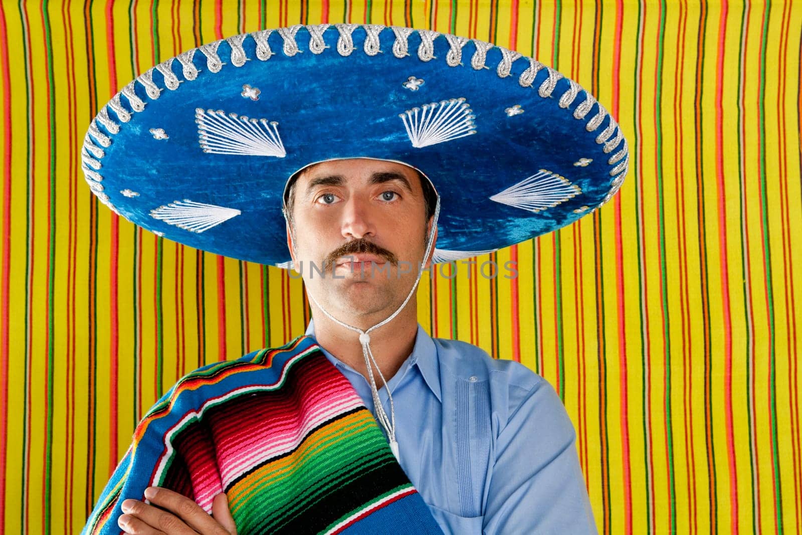 Mexican mustache man portrait with sombrero holding serape in shoulder