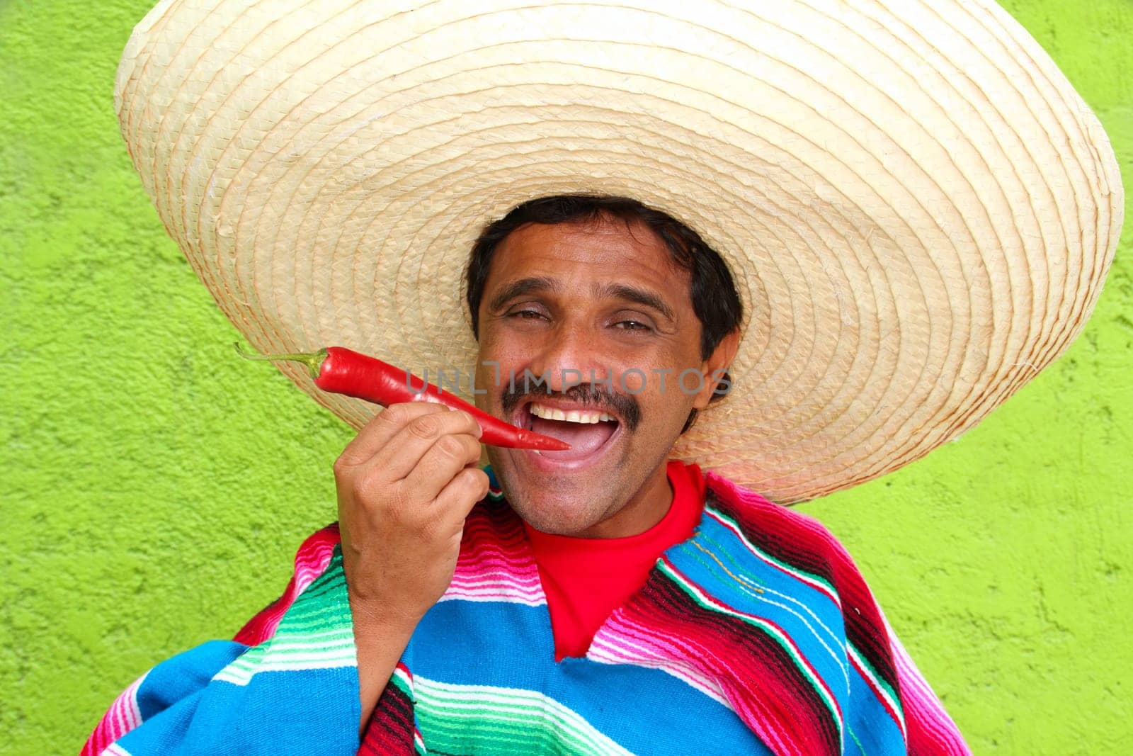 Mexican man poncho sombrero eating red chili hot pepper Mexico