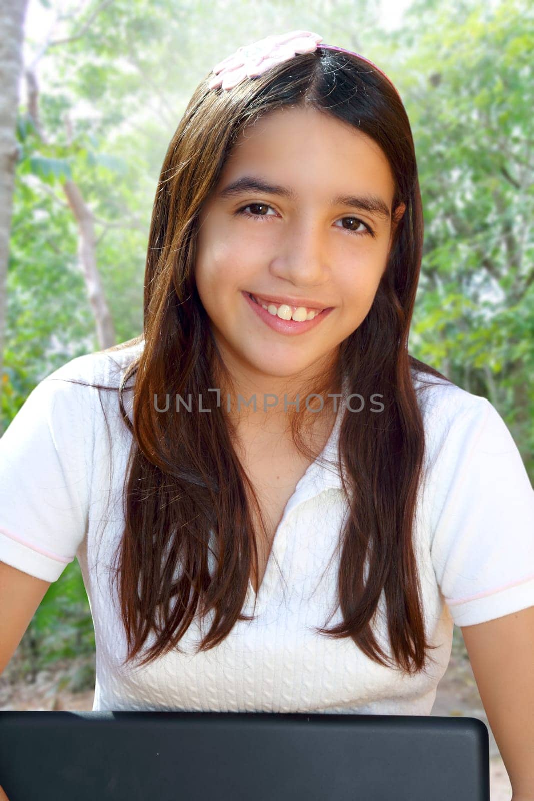 Latin teenager student smiling holding laptop park outdoor forest