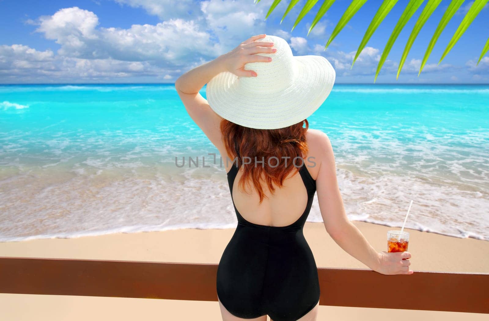 beach hat rear view woman cocktail tropical beach black swimsuit