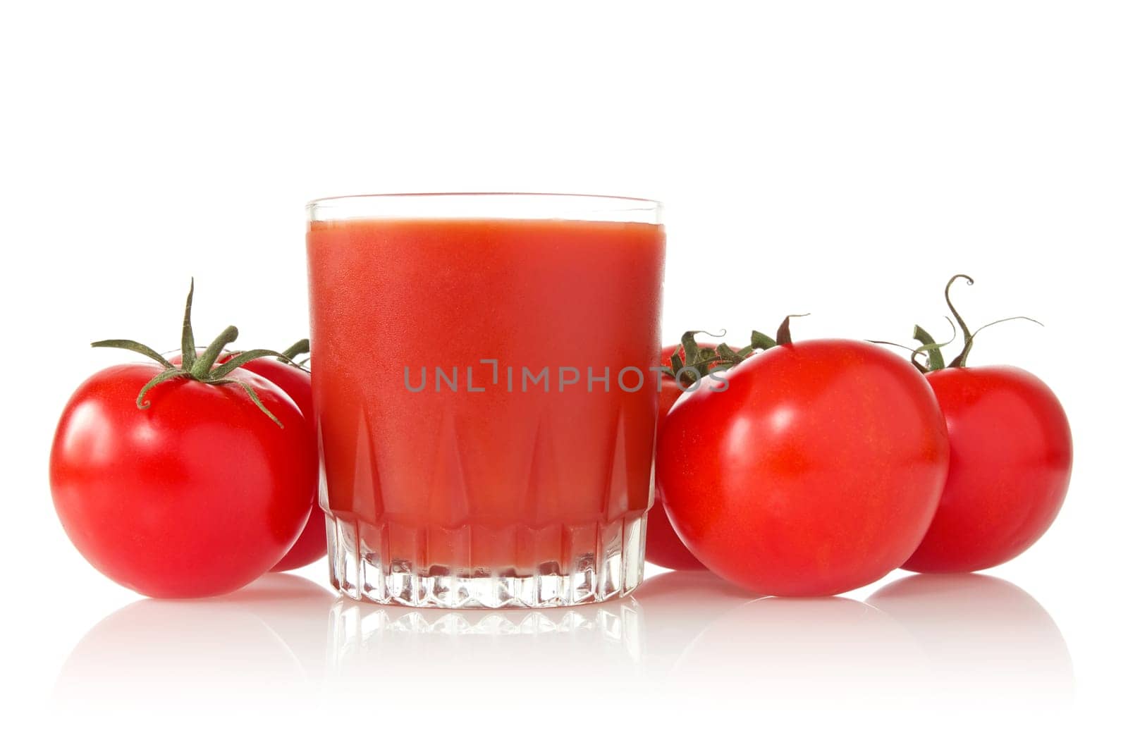 ripe tomatoes and glass of tomato juice over a white background