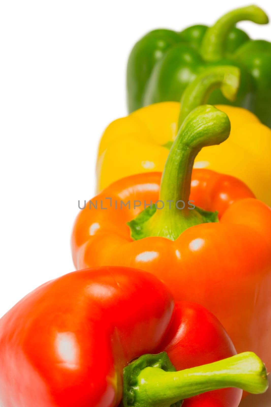 Orange, red, yellow and green peppers on a white background.
