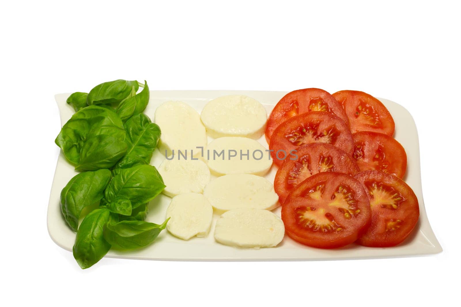 Tomato, fresh basil leaves and mozzarella in a white plate.