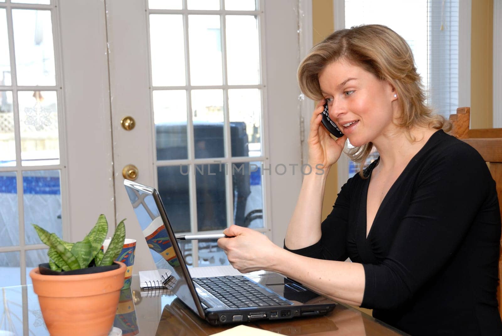 cute blond woamn on the phoone looking laptop data