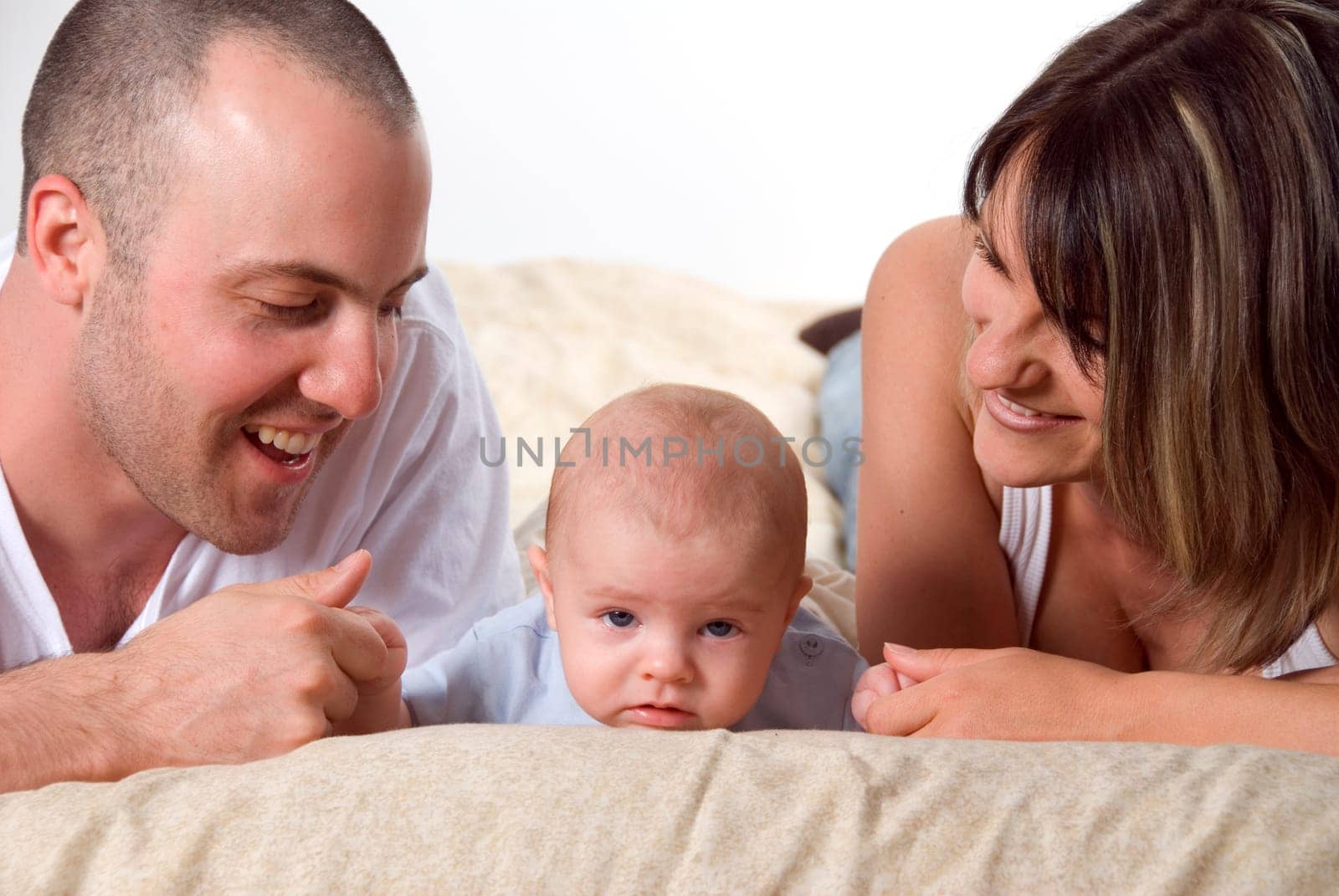 mom dad and the new born baby lying on the bed