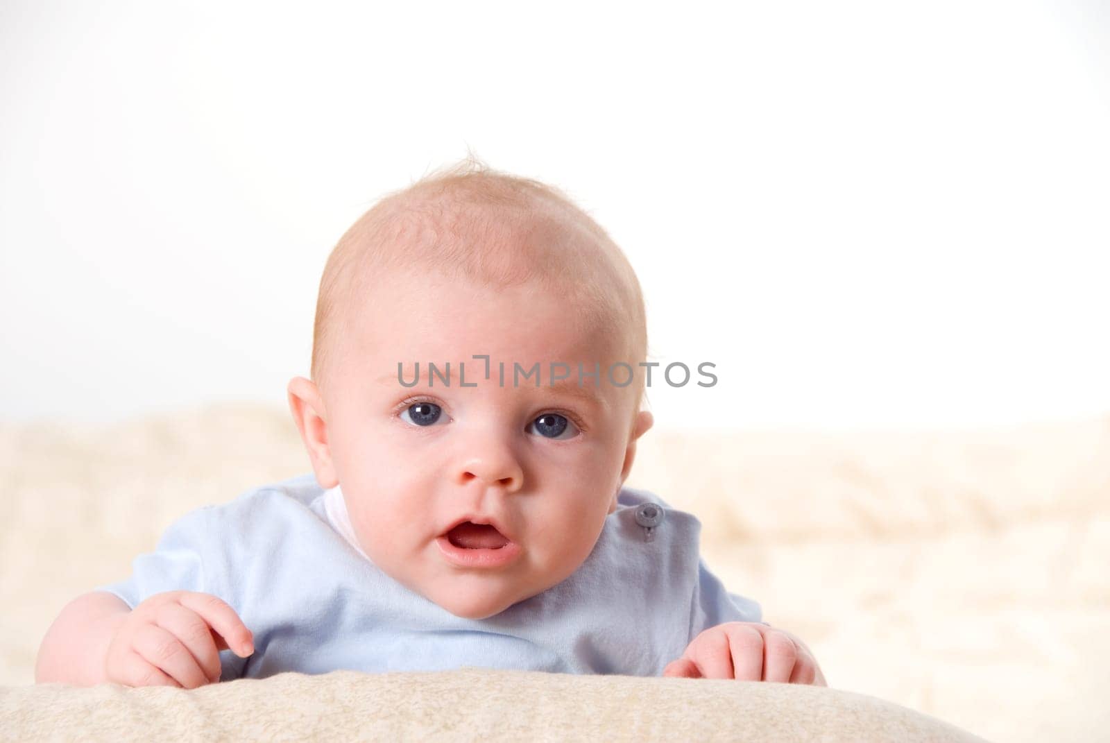 talking baby with blue eyes ona bed