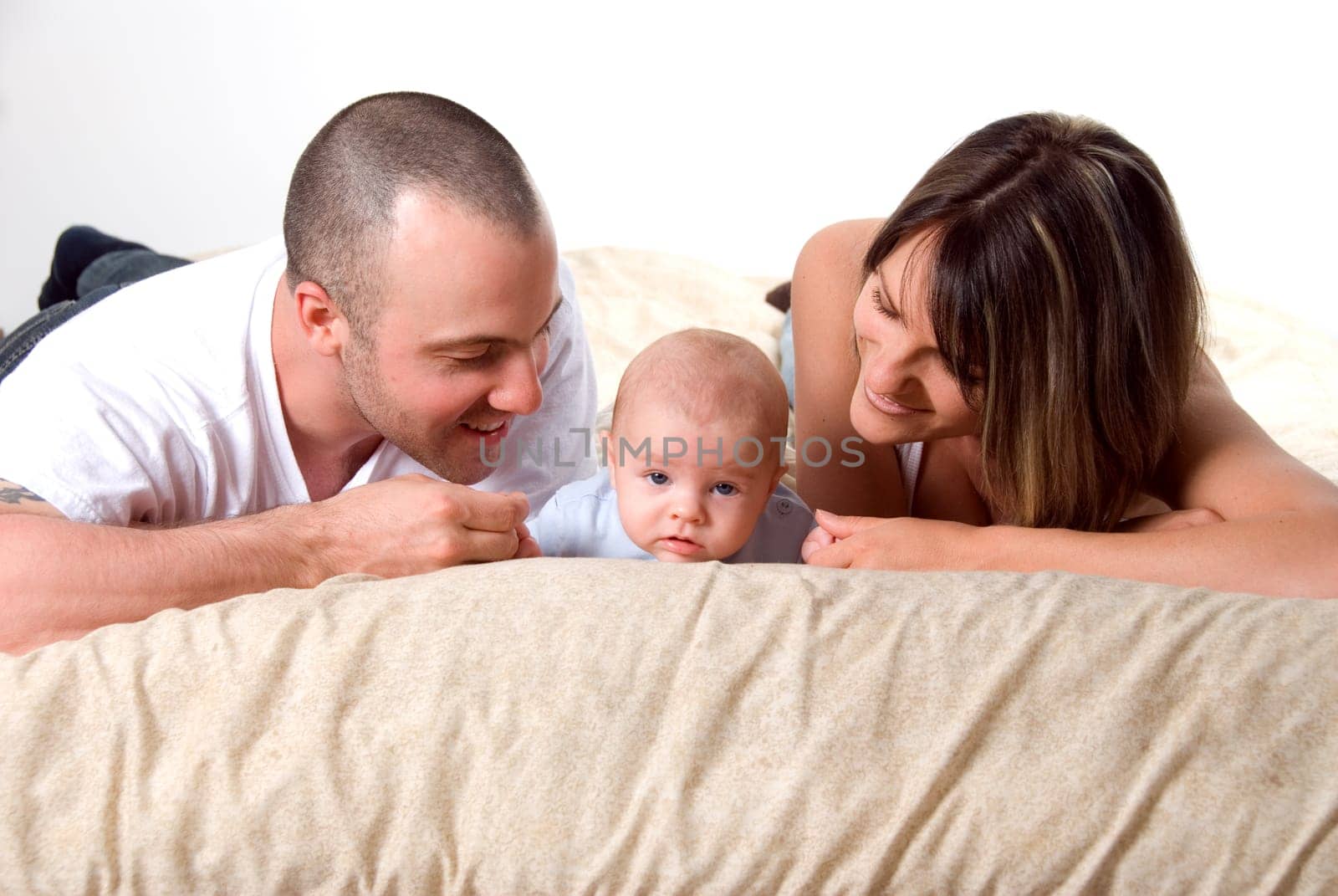 mom dad and the new born baby lying on the bed