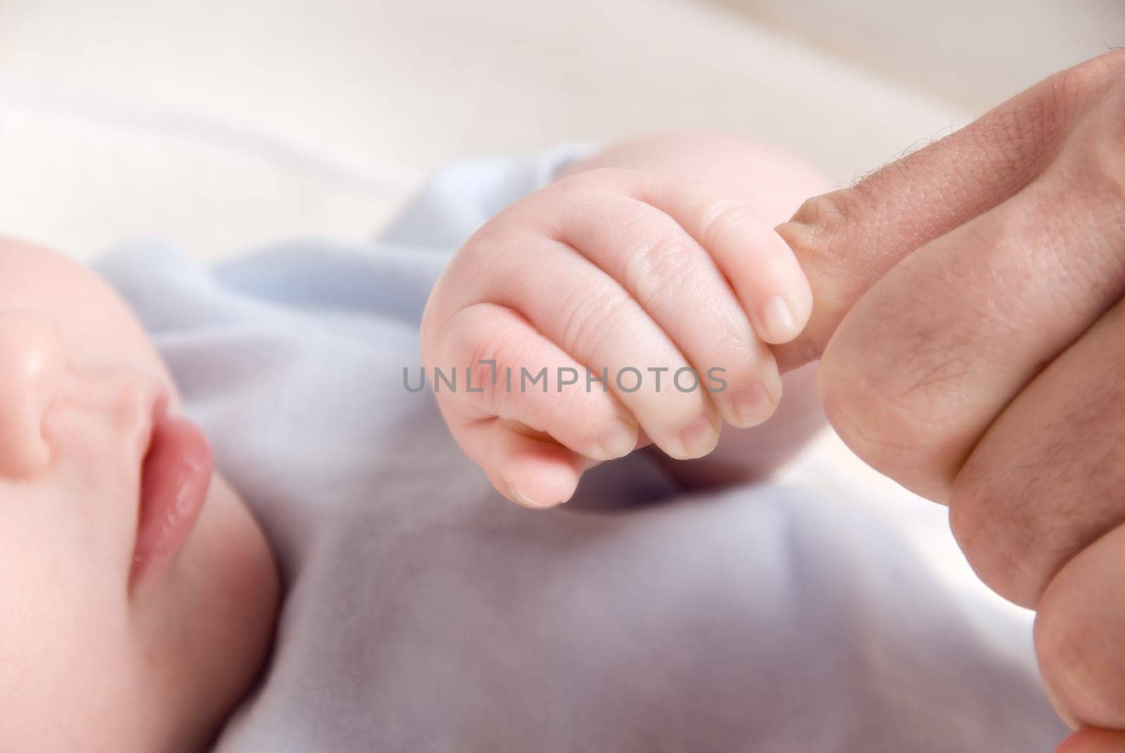 small baby hand holding on to dad's finger