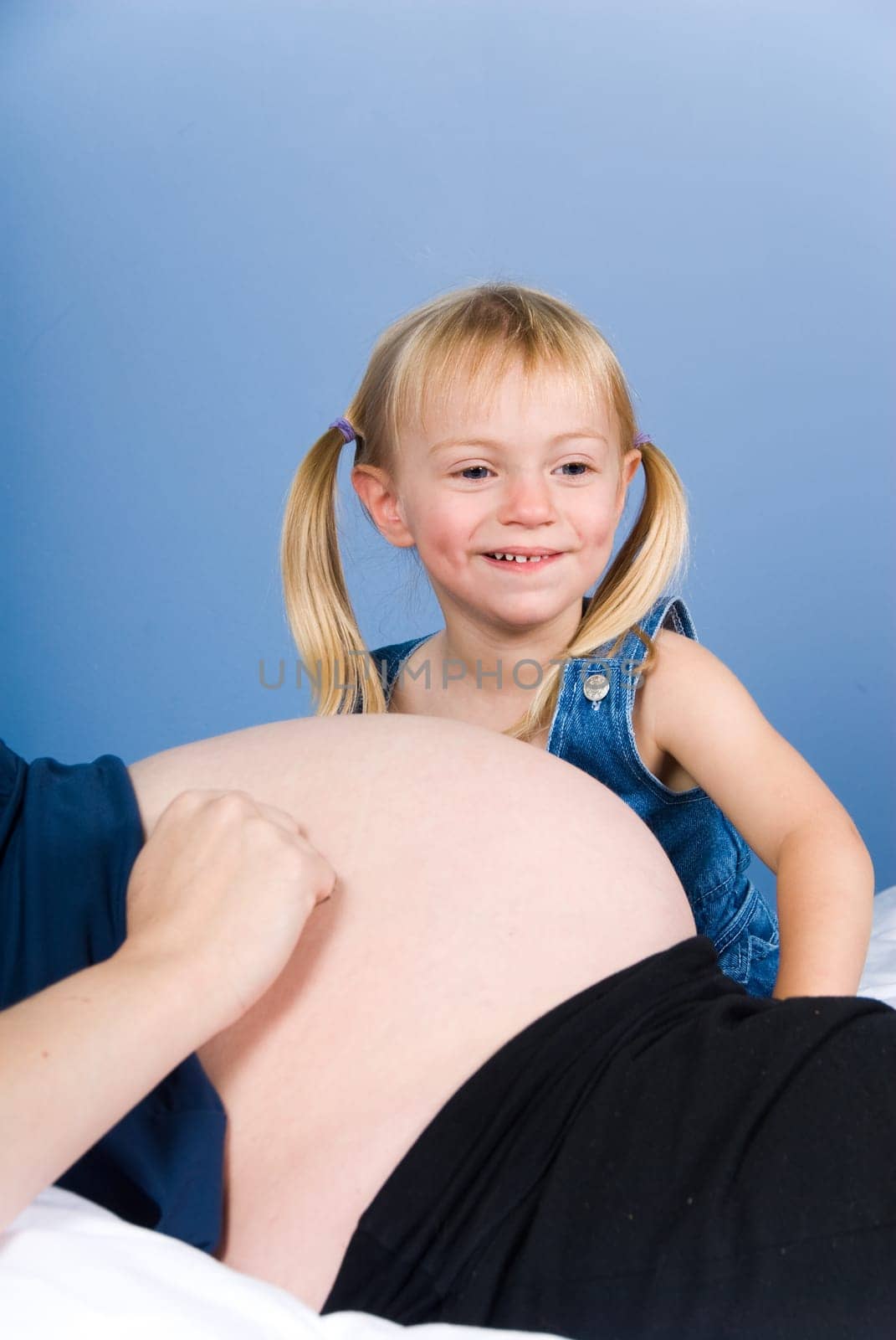 cute girl in blue hiding behing tummy