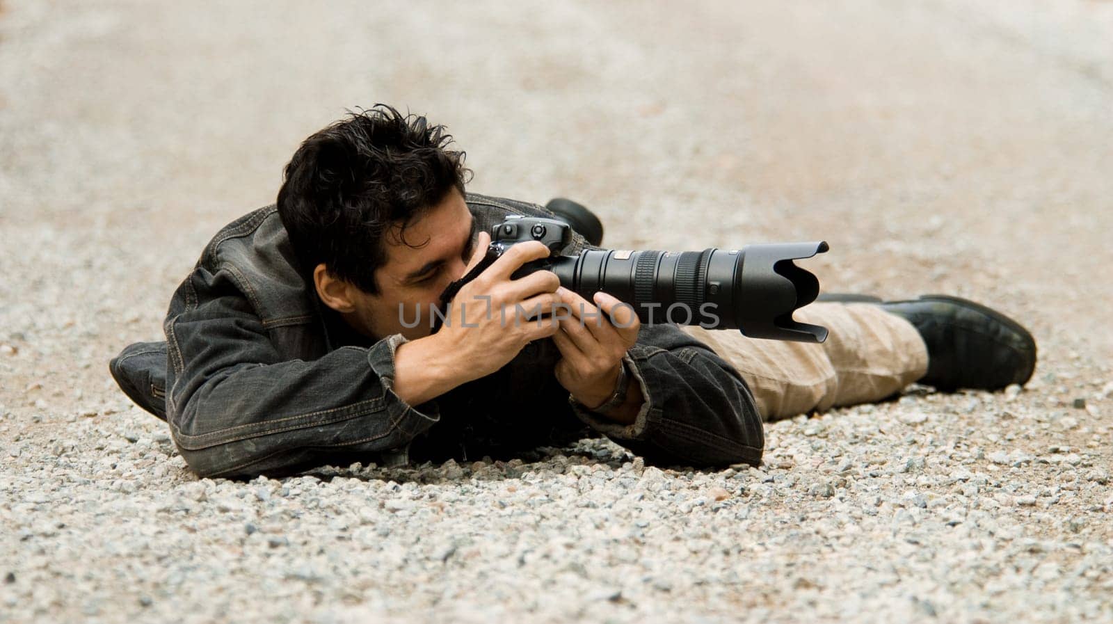 paparazzi photographer hiding on the ground to get shot