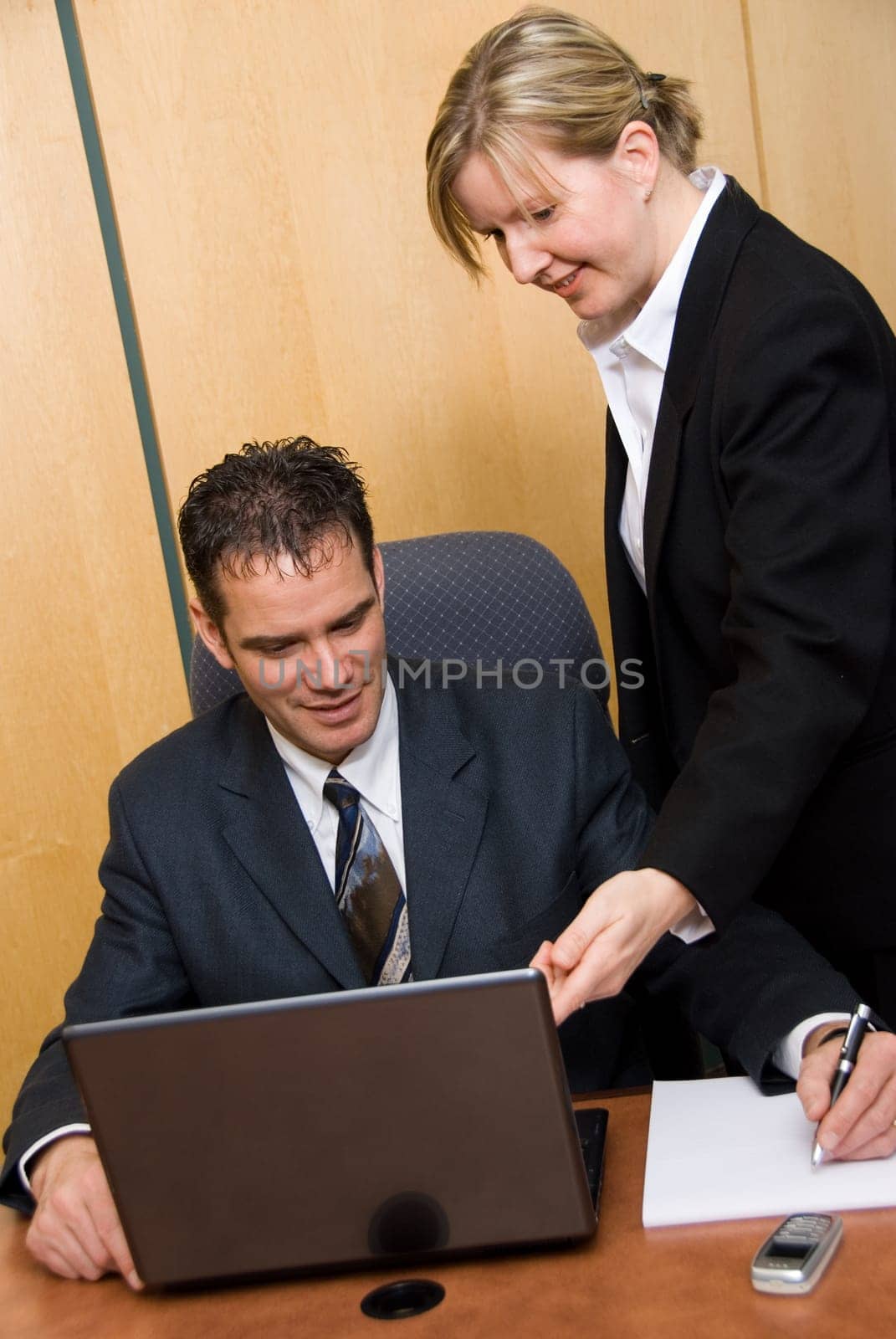 man and woman in a room with a laptop writing on paper