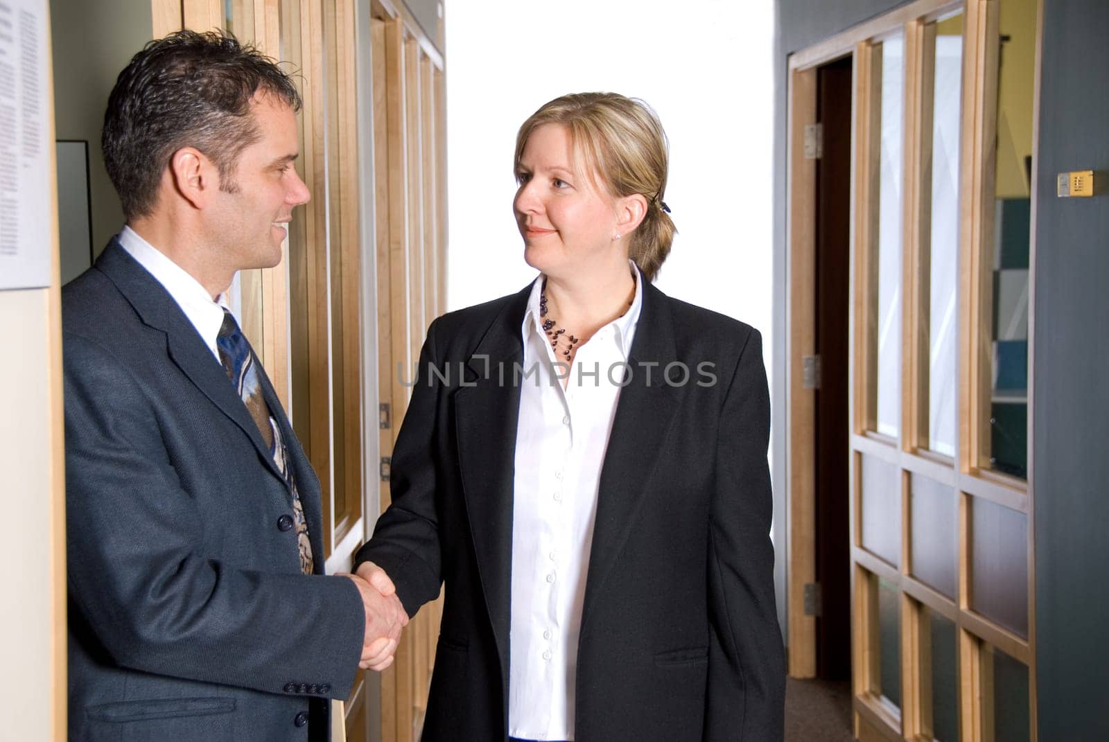 two business people shaking hands in the hallway