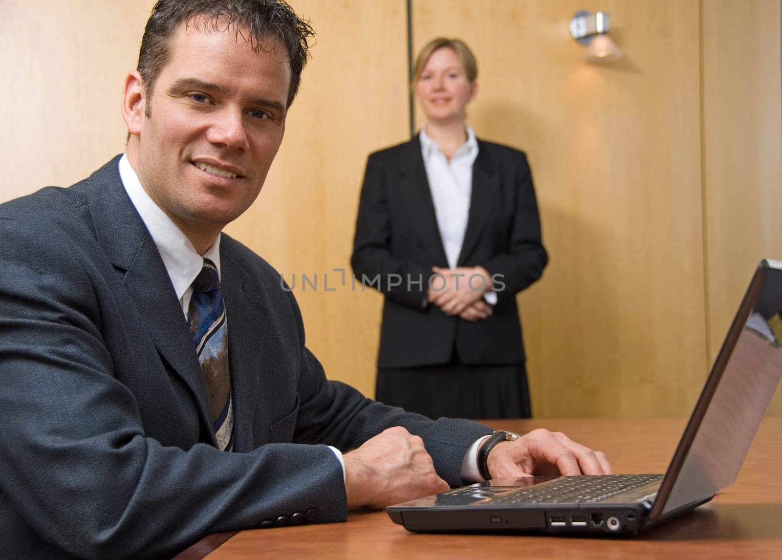 2 people looking at the camera with a laptop