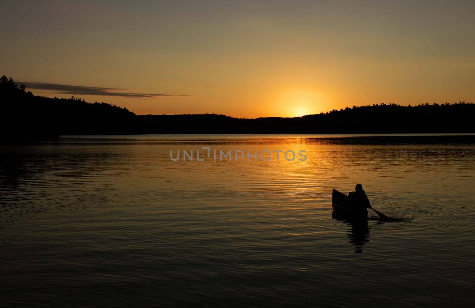 canoe on lake with sunset in silhouette