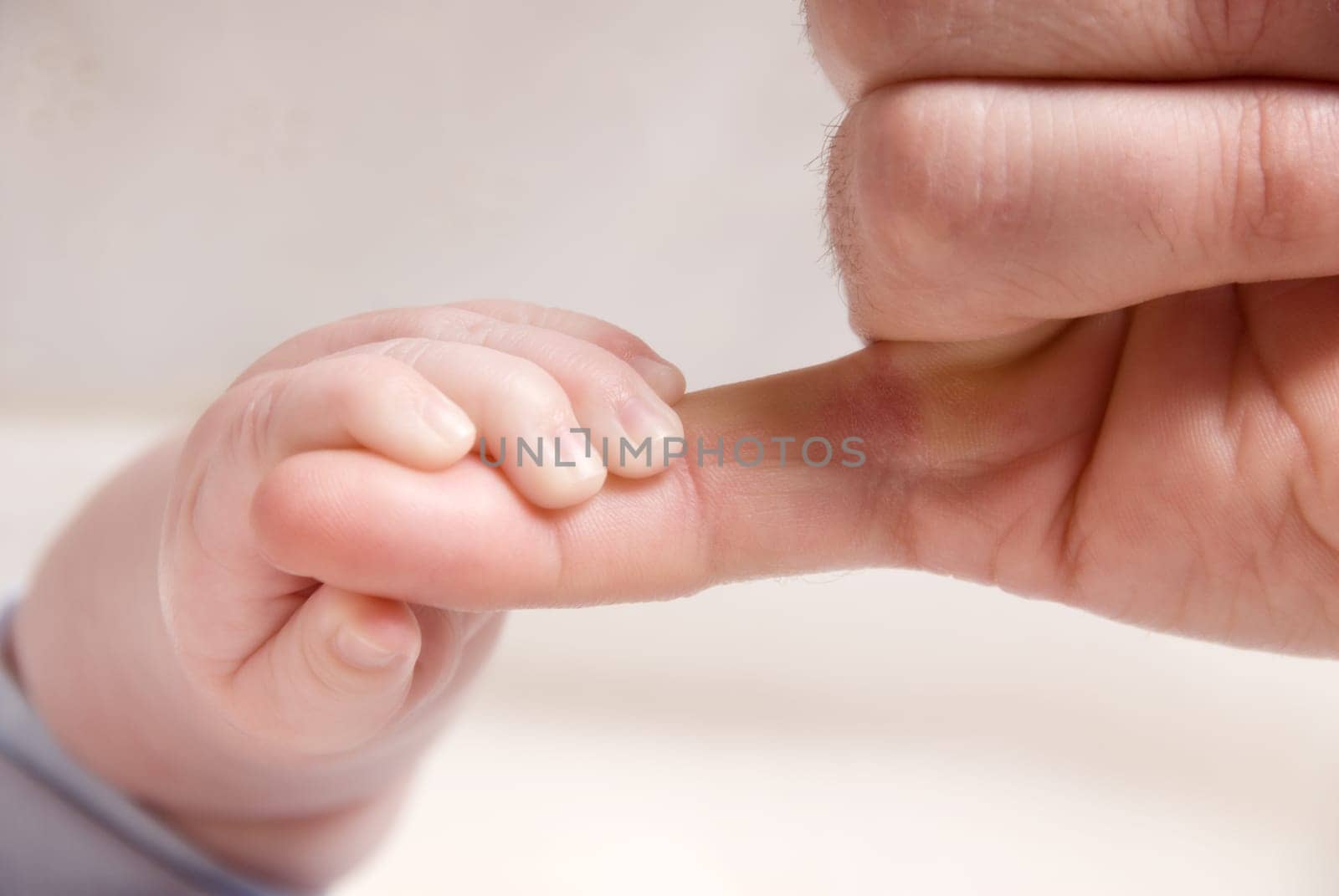 small baby hand holding on to dad's finger