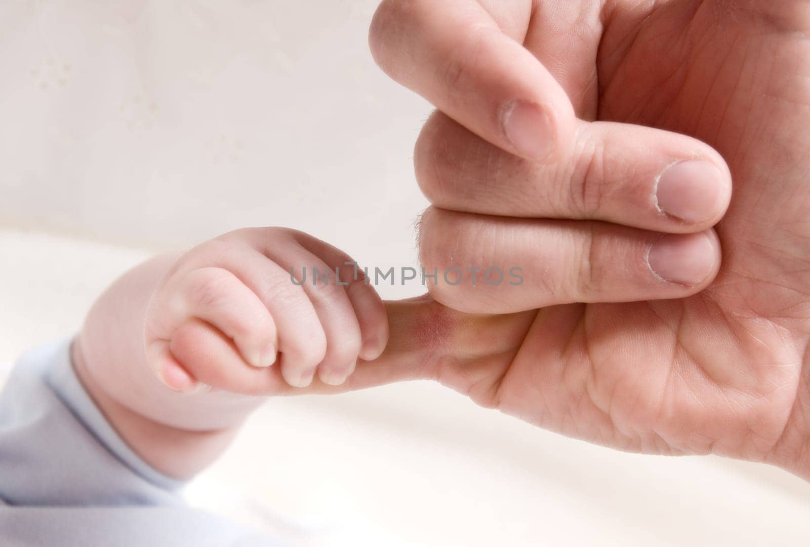 small baby hand holding on to dad's finger