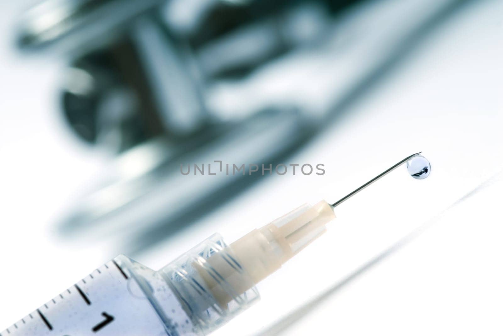 Stethoscope and a syringe in green on an isolated white background