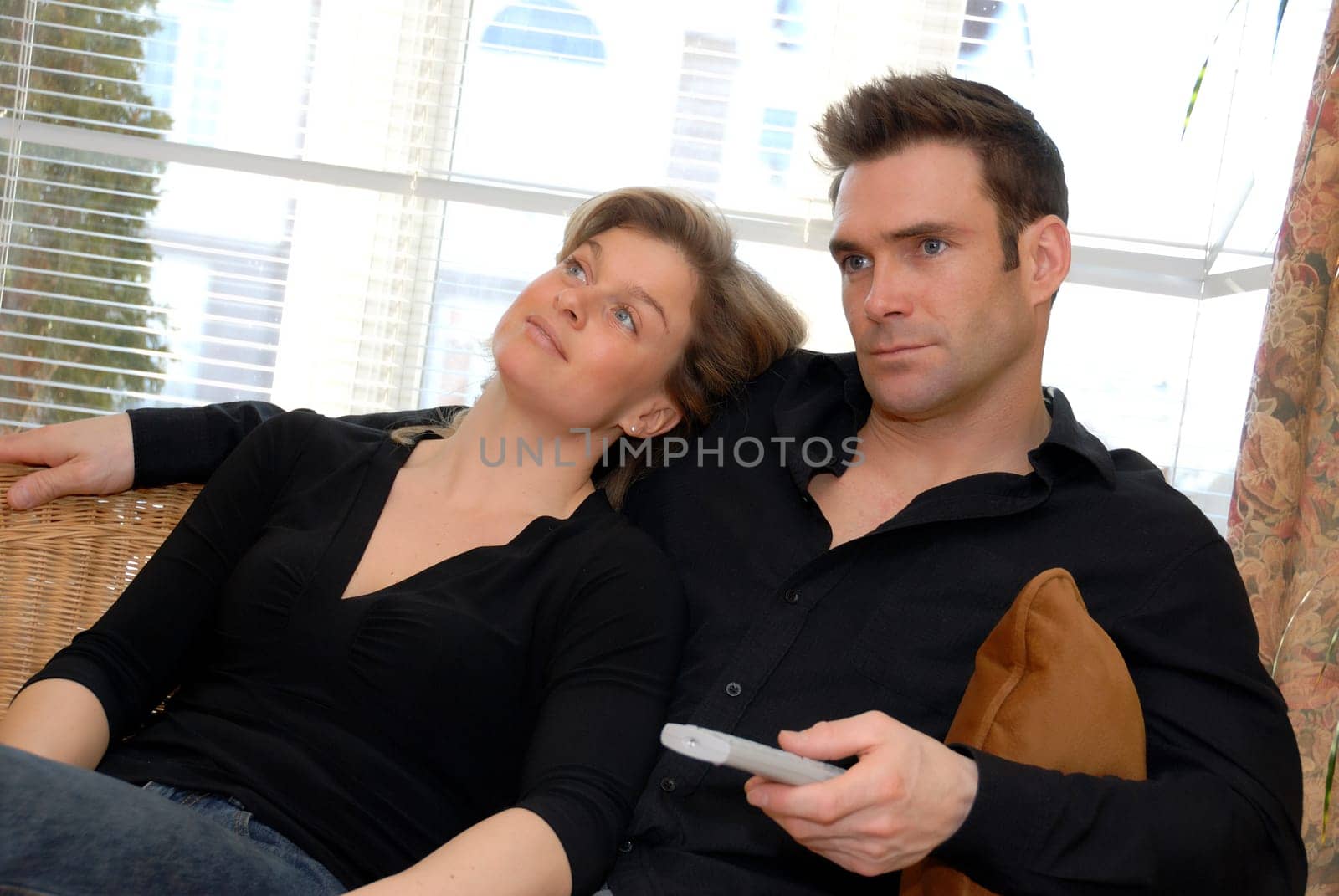 man watching TV whicle woman sits back bored