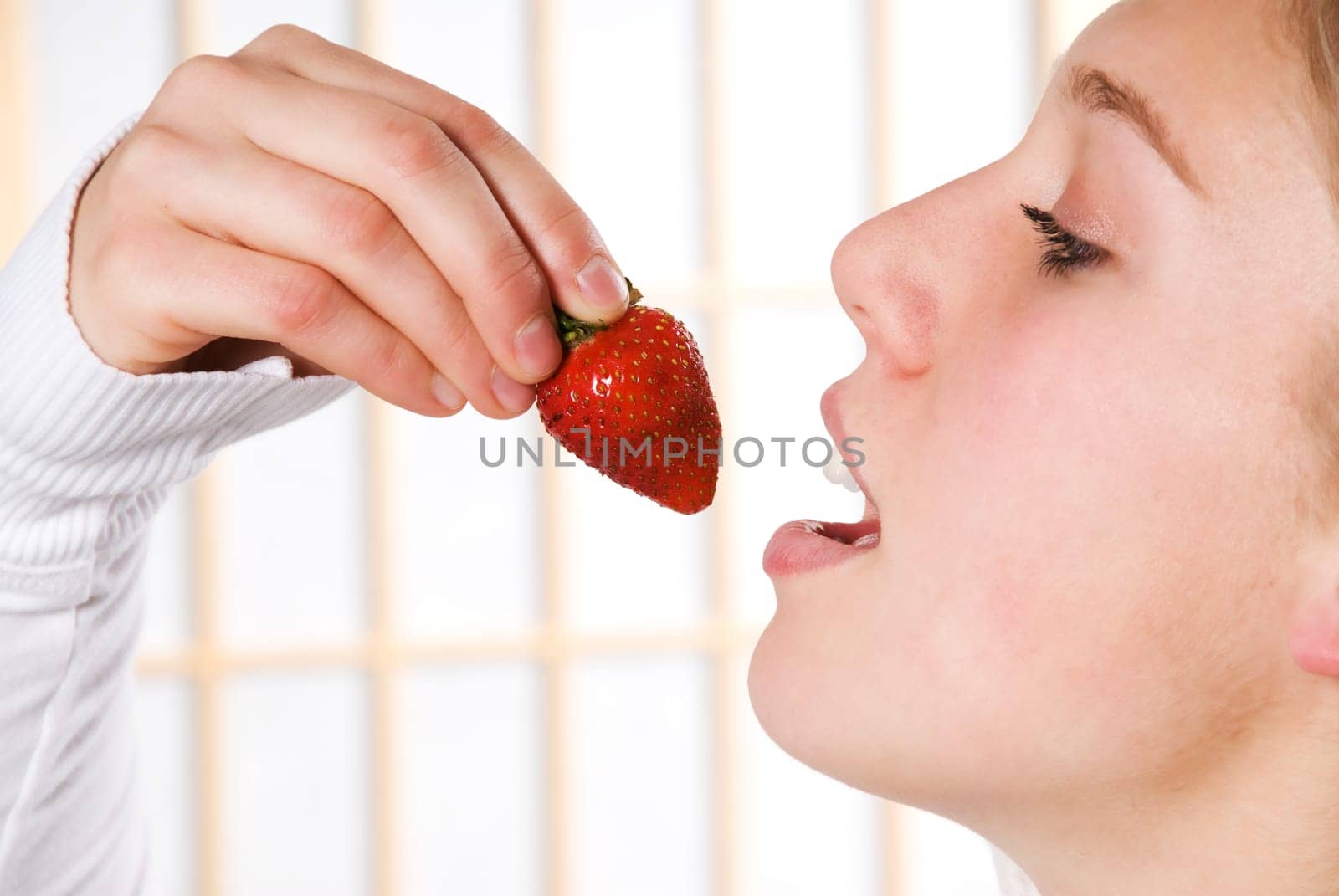 young woman eating a strawberry for health