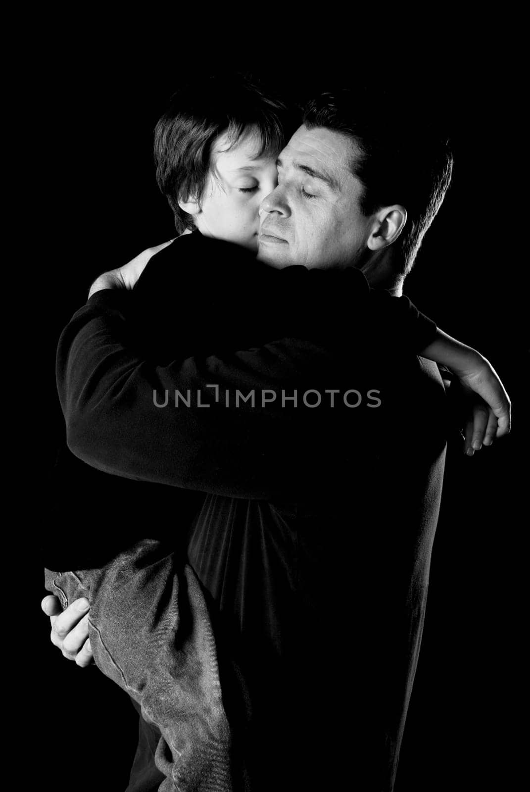Dad and son in an embrace on black
