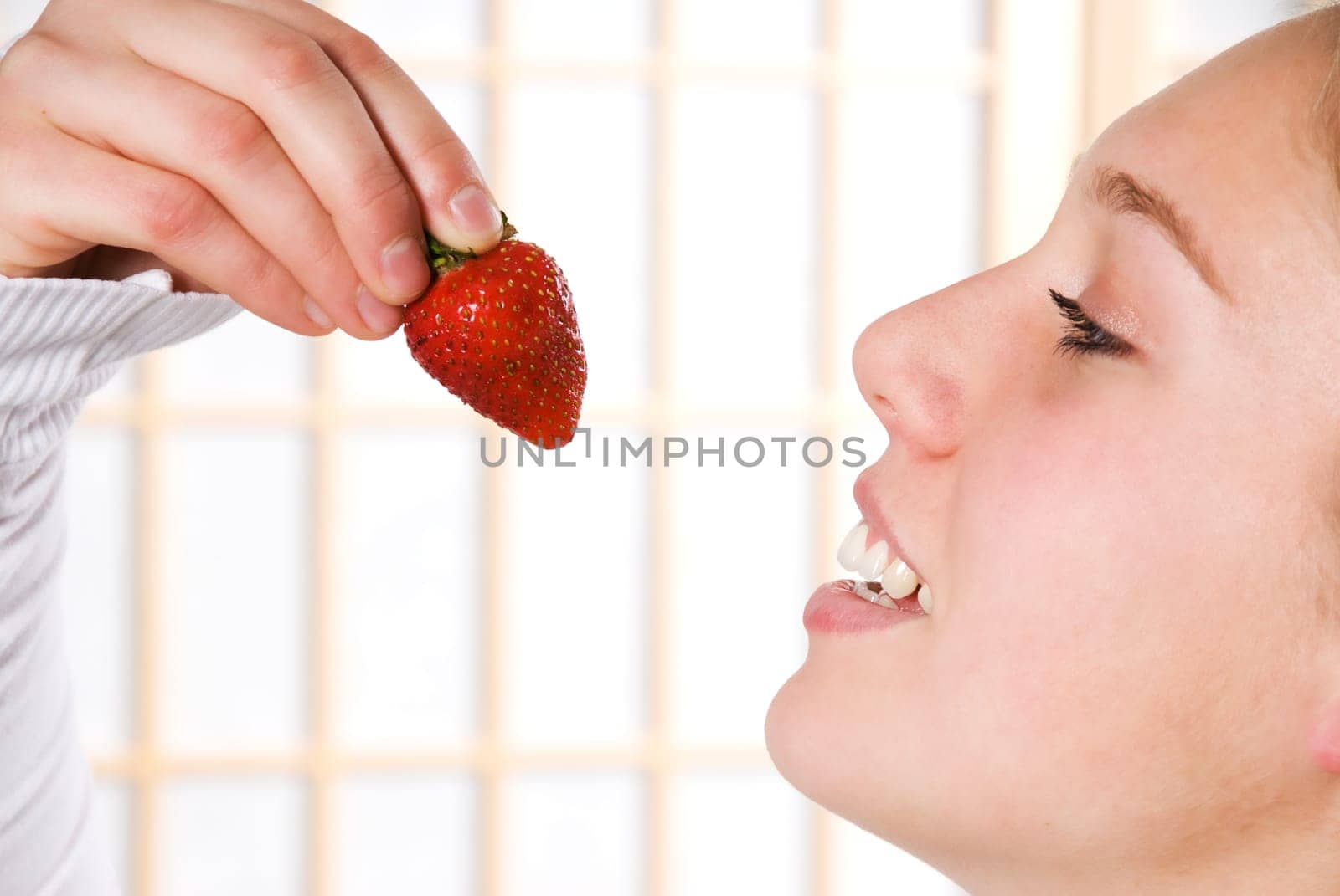 young woman eating a strawberry for health