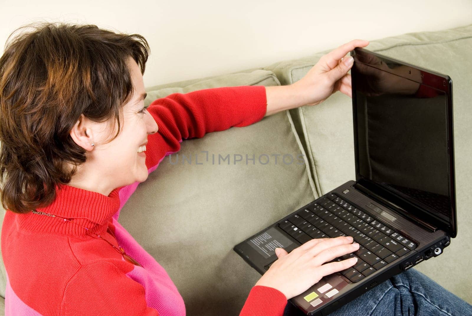 woman in red sitting on the sofa with laptop