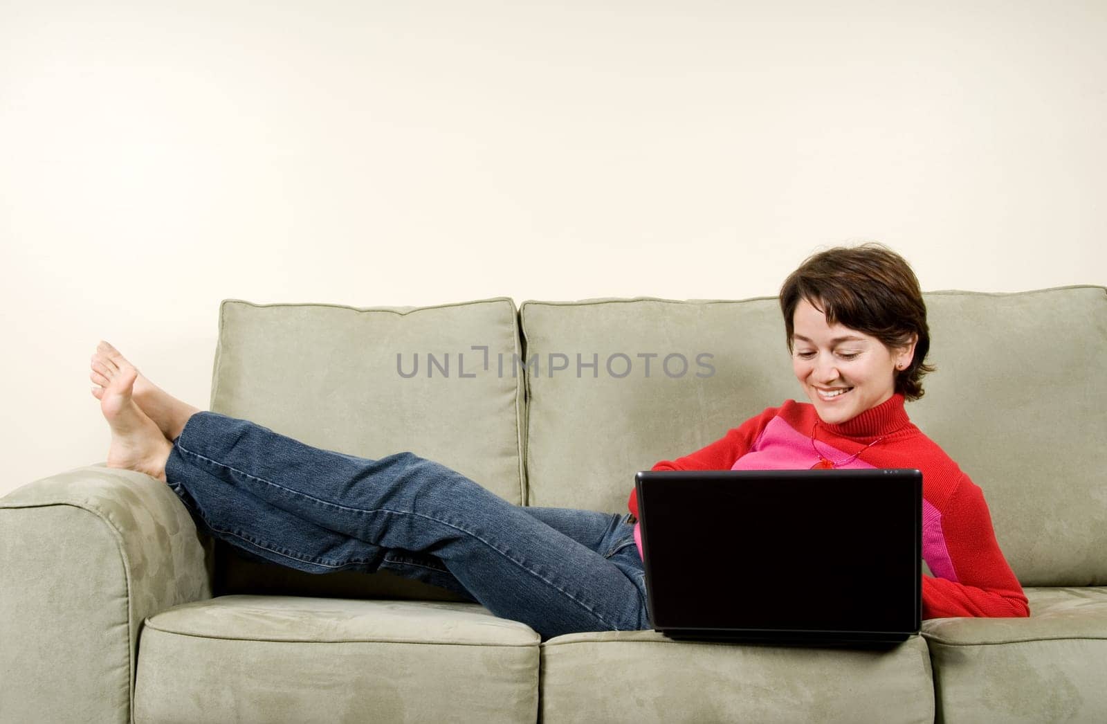 woman lying on couch on the laptop