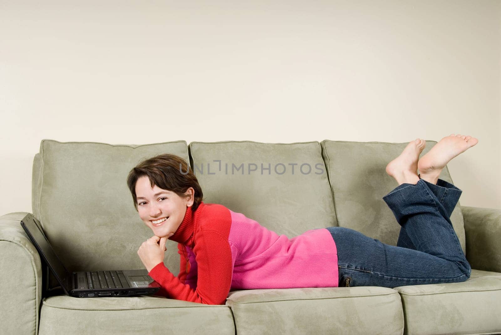 young woman happy on couch with laptop