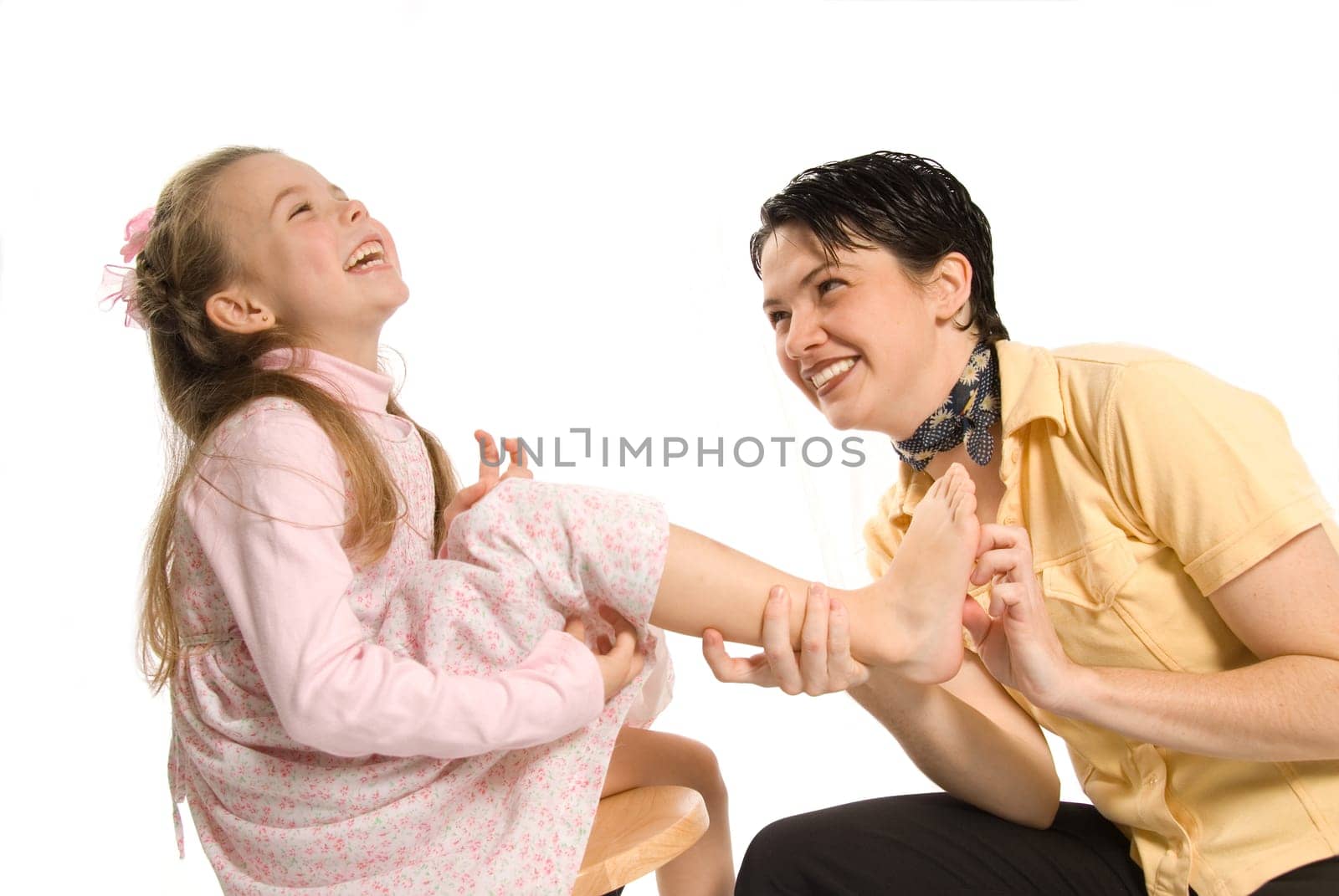 mom tickling daughter on white background laughing