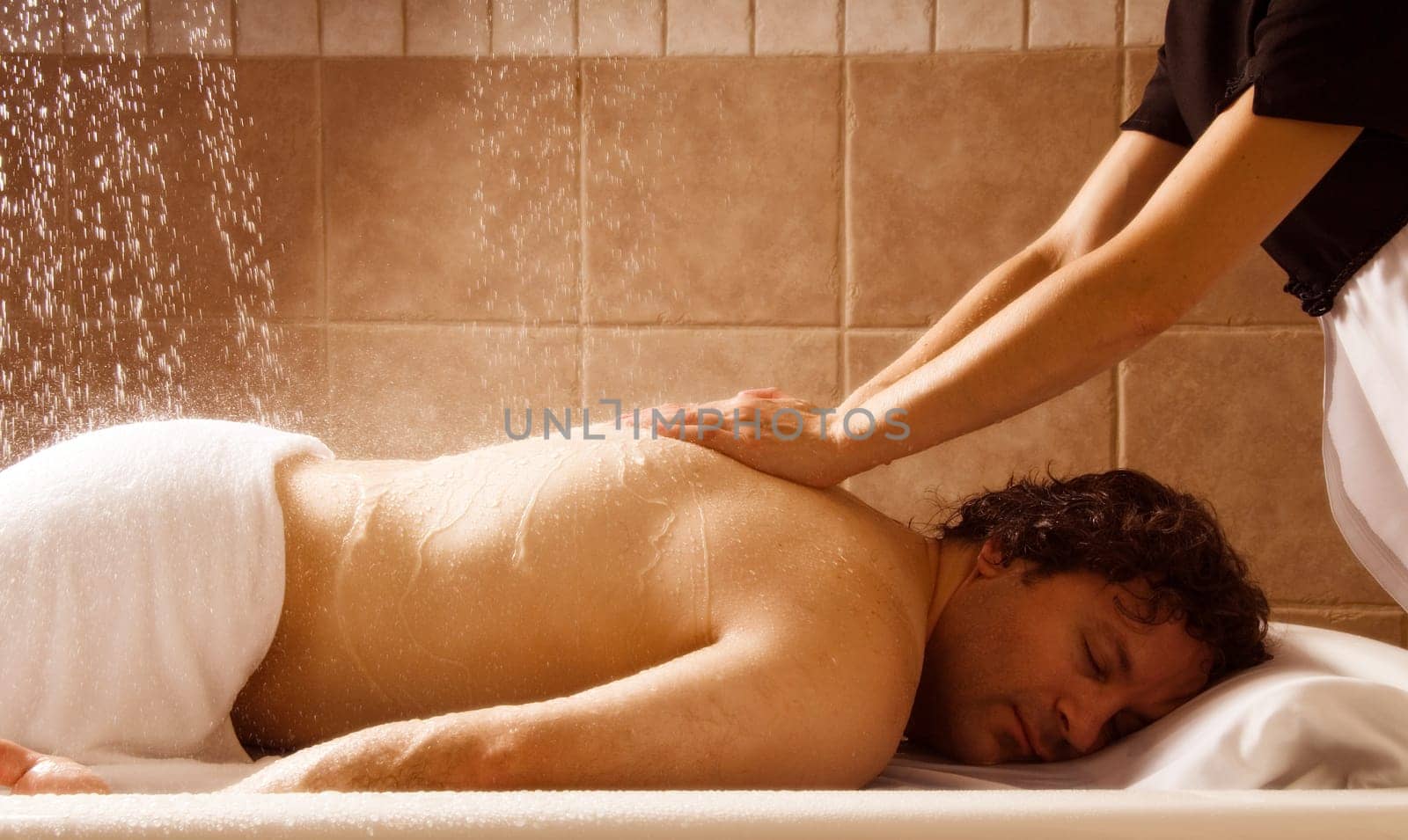 man getting a massage with water in a spa