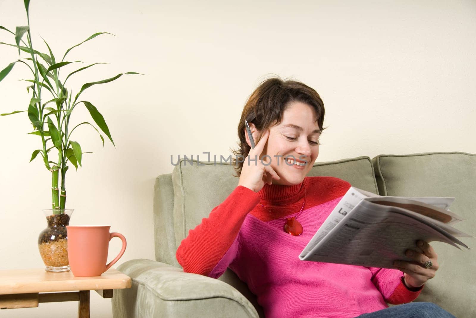 smiling woman reading the newspaper with pen